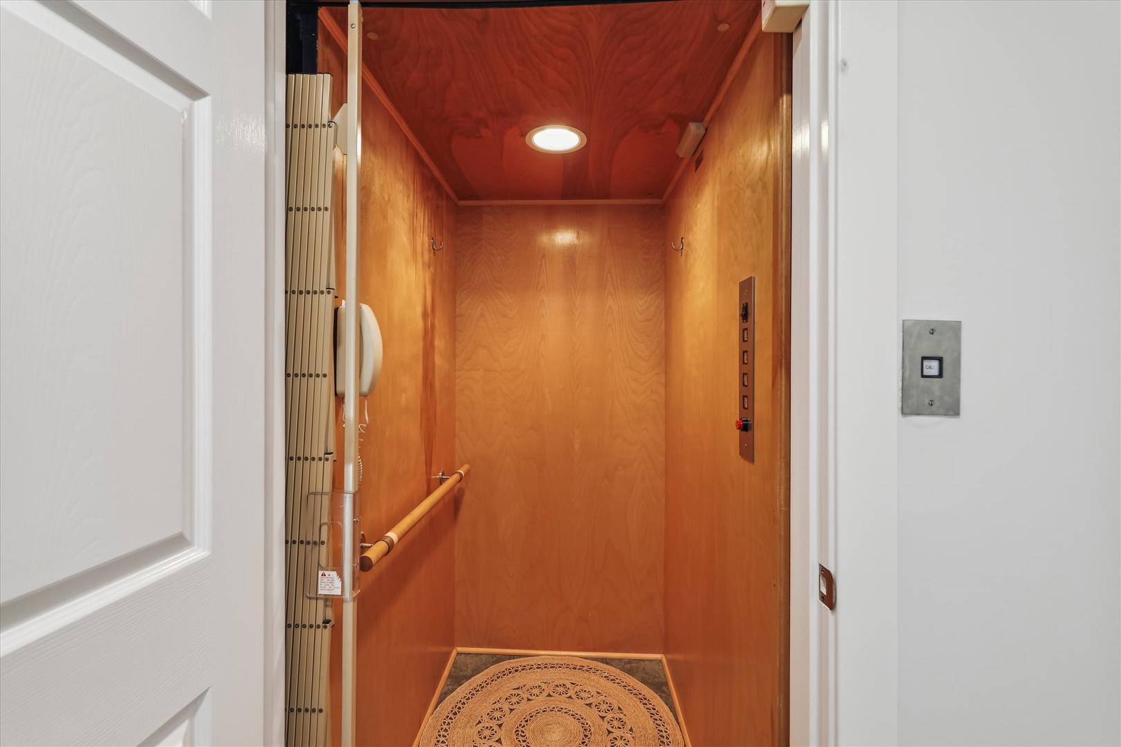 This private elevator offers convenient access between floors, featuring warm wood paneling and a safety handrail for your comfort.
