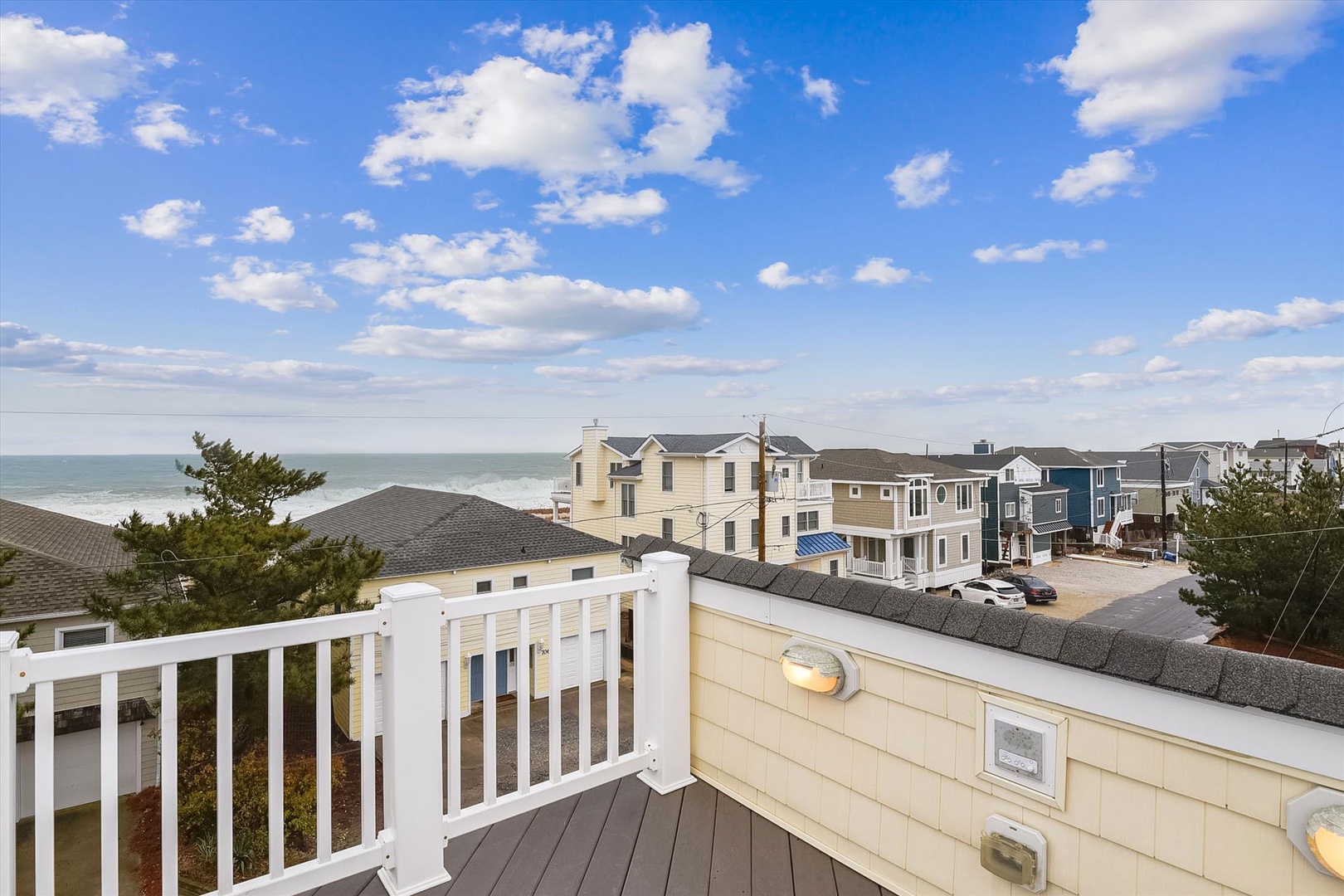 Elevated coastal views showcase the property's prime beachside location, with neighboring homes lining the shore and the sea stretching toward the horizon under a peaceful sky.