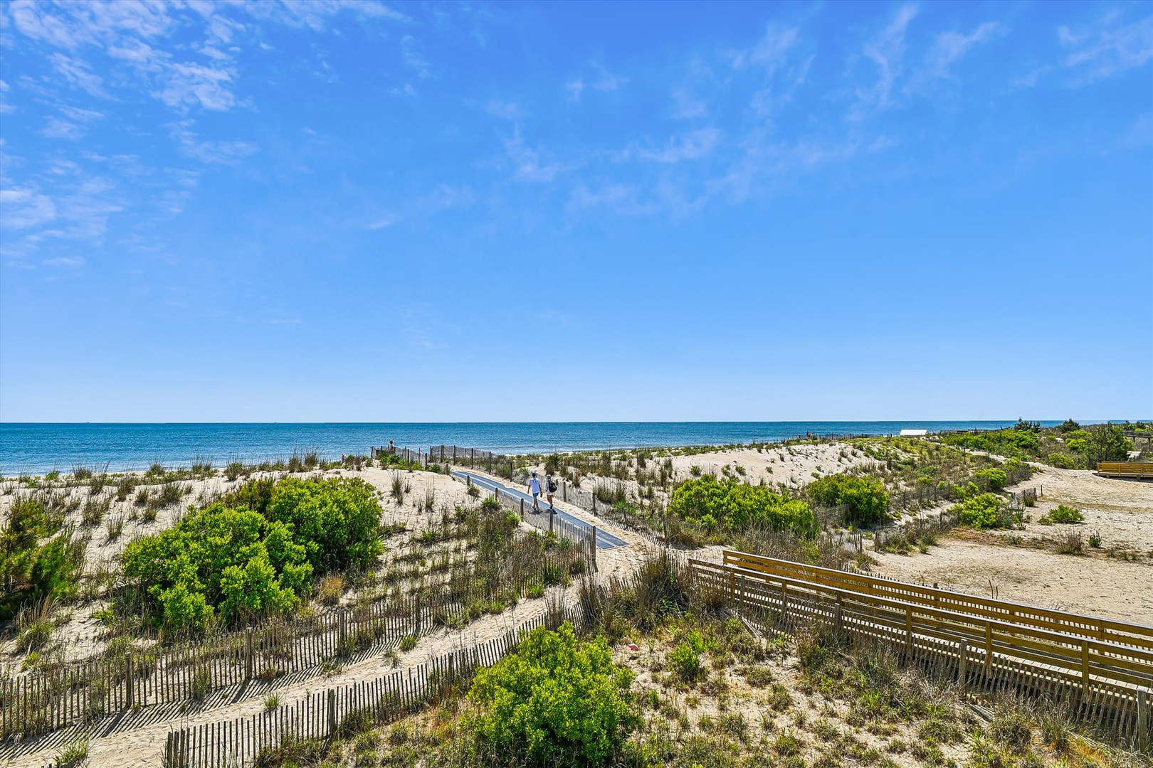 A pristine coastal boardwalk winds through natural dunes to the turquoise waters beyond, part of the property's beachfront location and surrounding area.