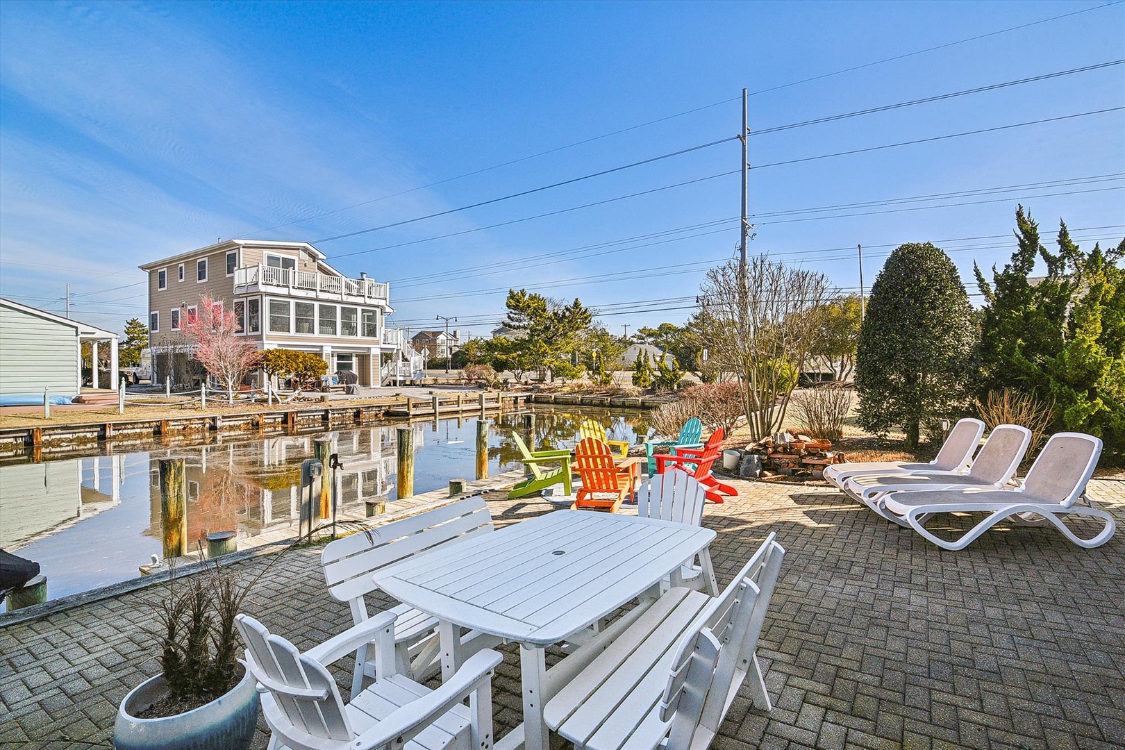 Waterfront vacation rental with private dock and colorful Adirondack chairs overlooking the canal.