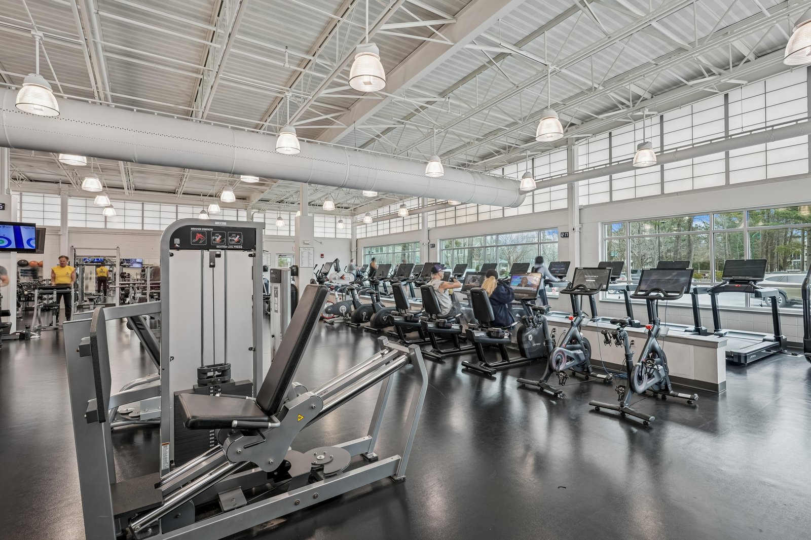 Modern fitness center features abundant natural light, brand-new cardio and strength equipment, and a spacious layout for your daily workout routine.
