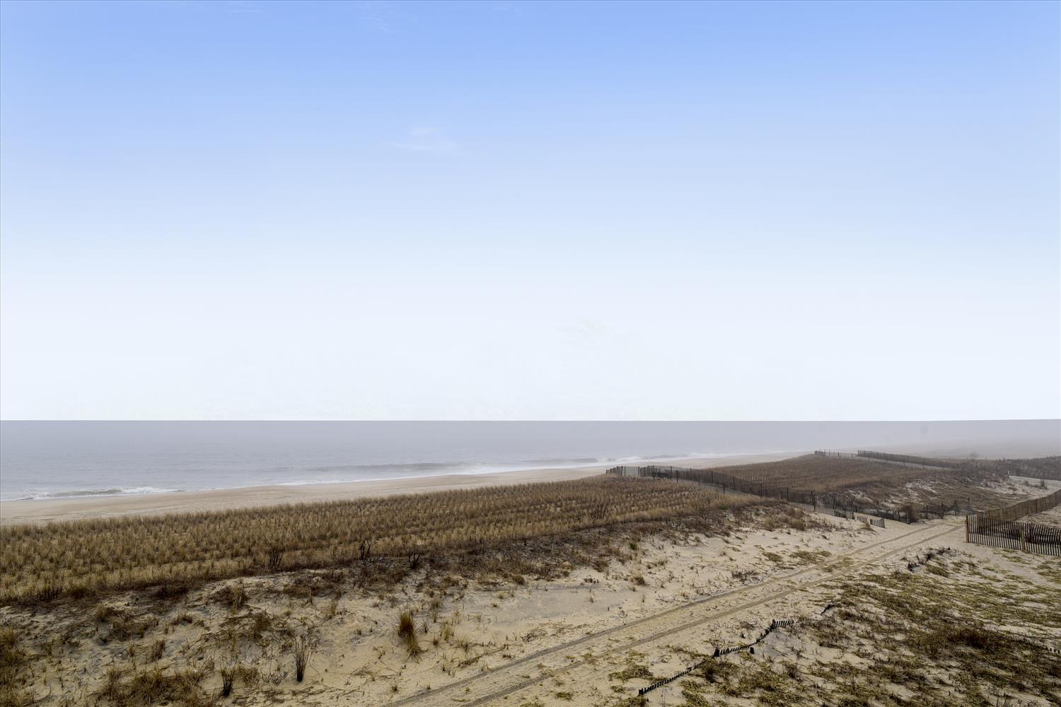 Expansive coastal scenery with pristine sandy beach stretching along the shoreline, framed by natural dune vegetation.