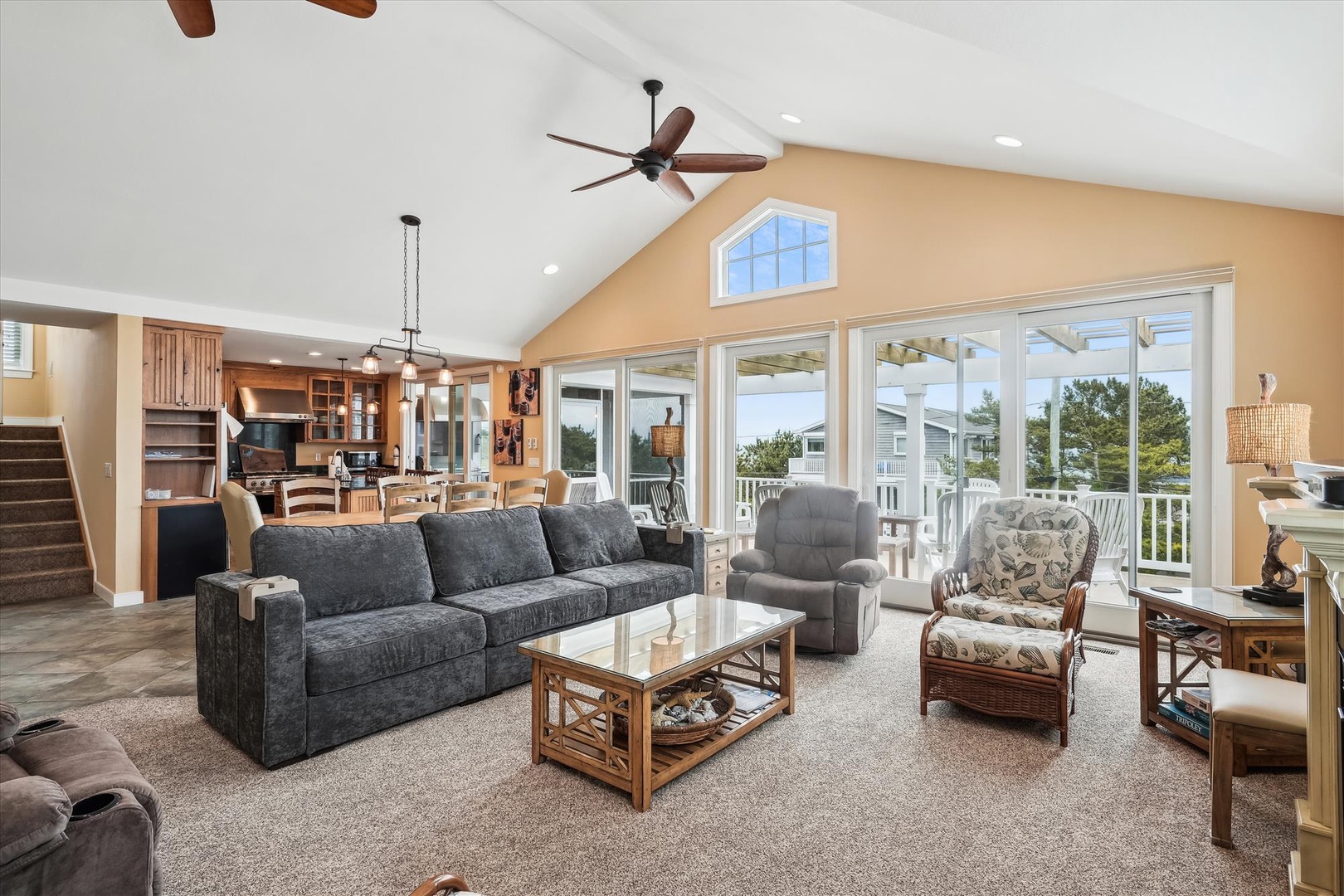 Relax in your spacious living room featuring vaulted ceilings, cozy seating, and stunning views of the surrounding trees through expansive glass doors that open to your private deck.