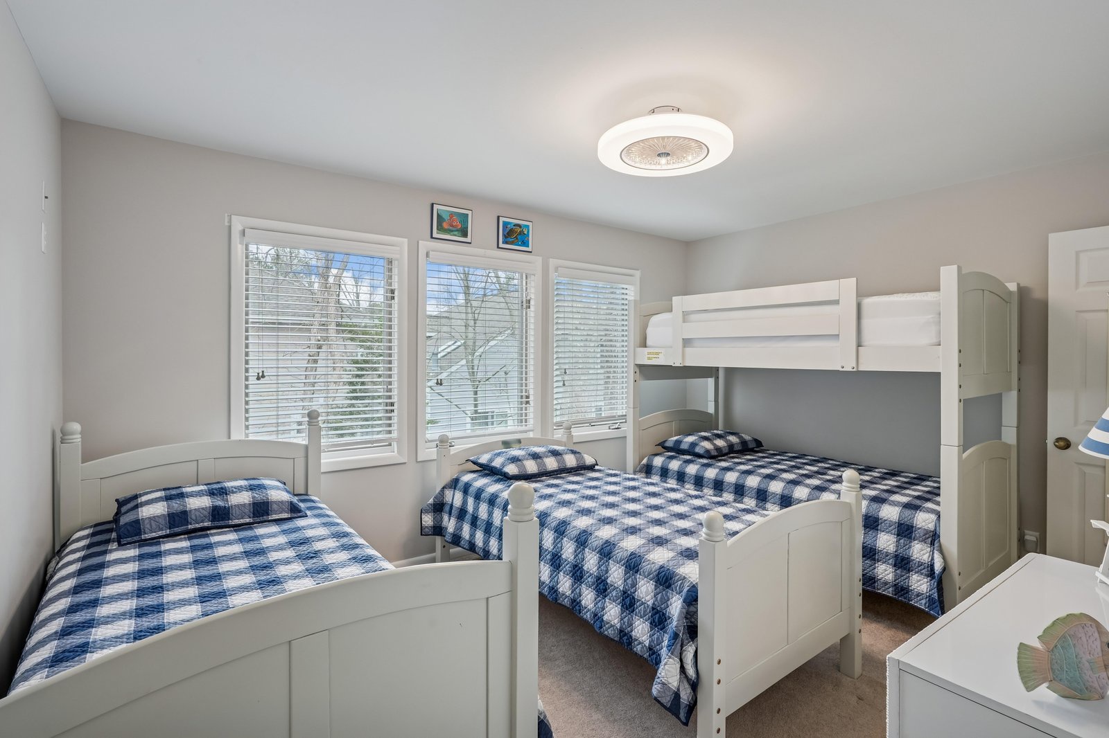 Your cheerful retreat with crisp white furniture and plaid linens, where sunny windows invite natural light and restful slumber awaits after each adventure-filled day.
