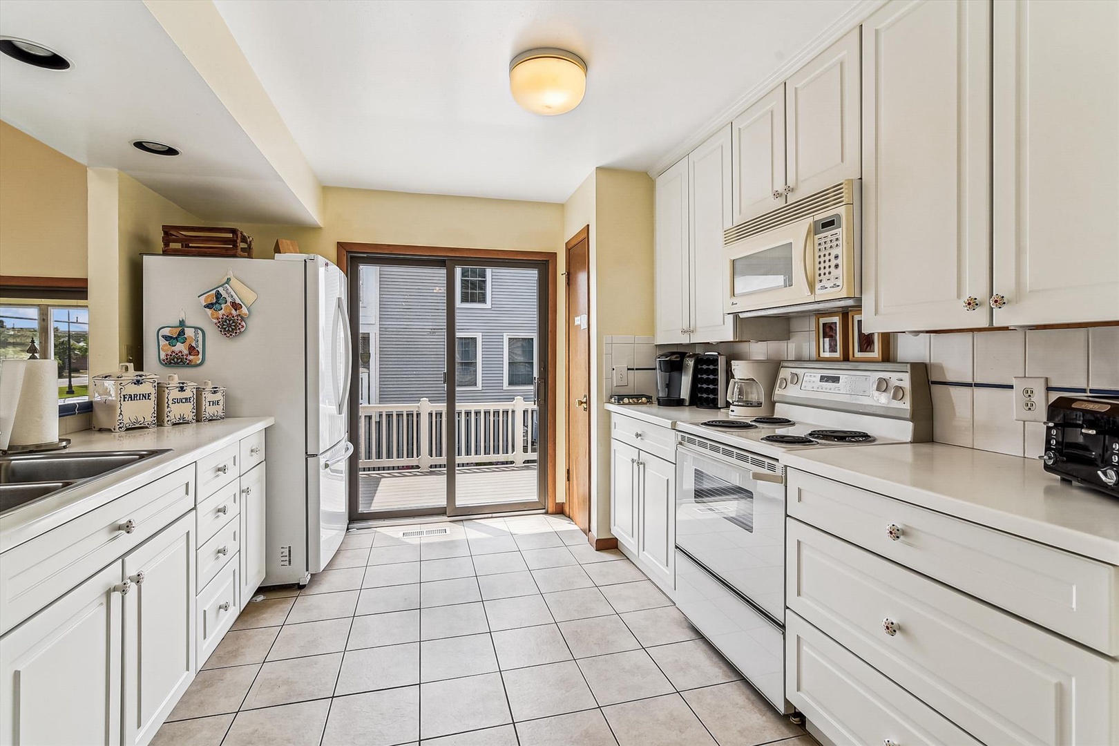 Step into your spacious, sunlit kitchen with crisp white cabinetry, modern appliances, and direct access to your private deck where morning coffee awaits.