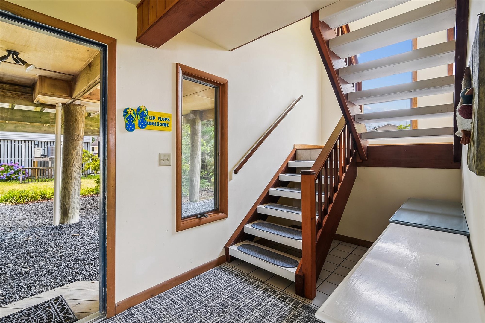 Step inside and feel instantly at home. Your private entrance opens to a welcoming entryway with cheerful touches, warm wood tones, and stairs leading to your cozy retreat.