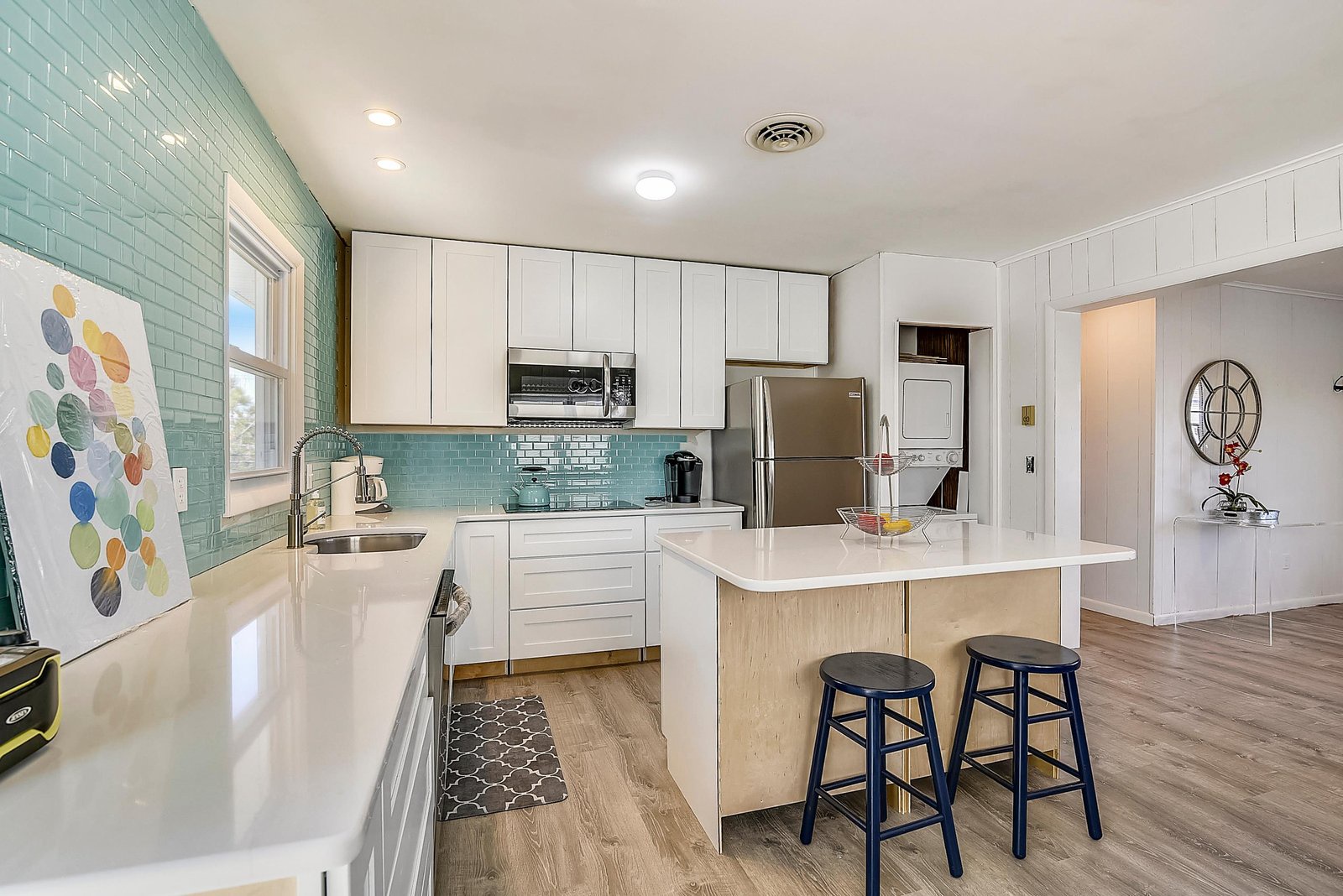 Whip up your favorite meals in this bright, modern kitchen featuring sleek white cabinetry, stainless steel appliances, and a breakfast island where you can sip your morning coffee.