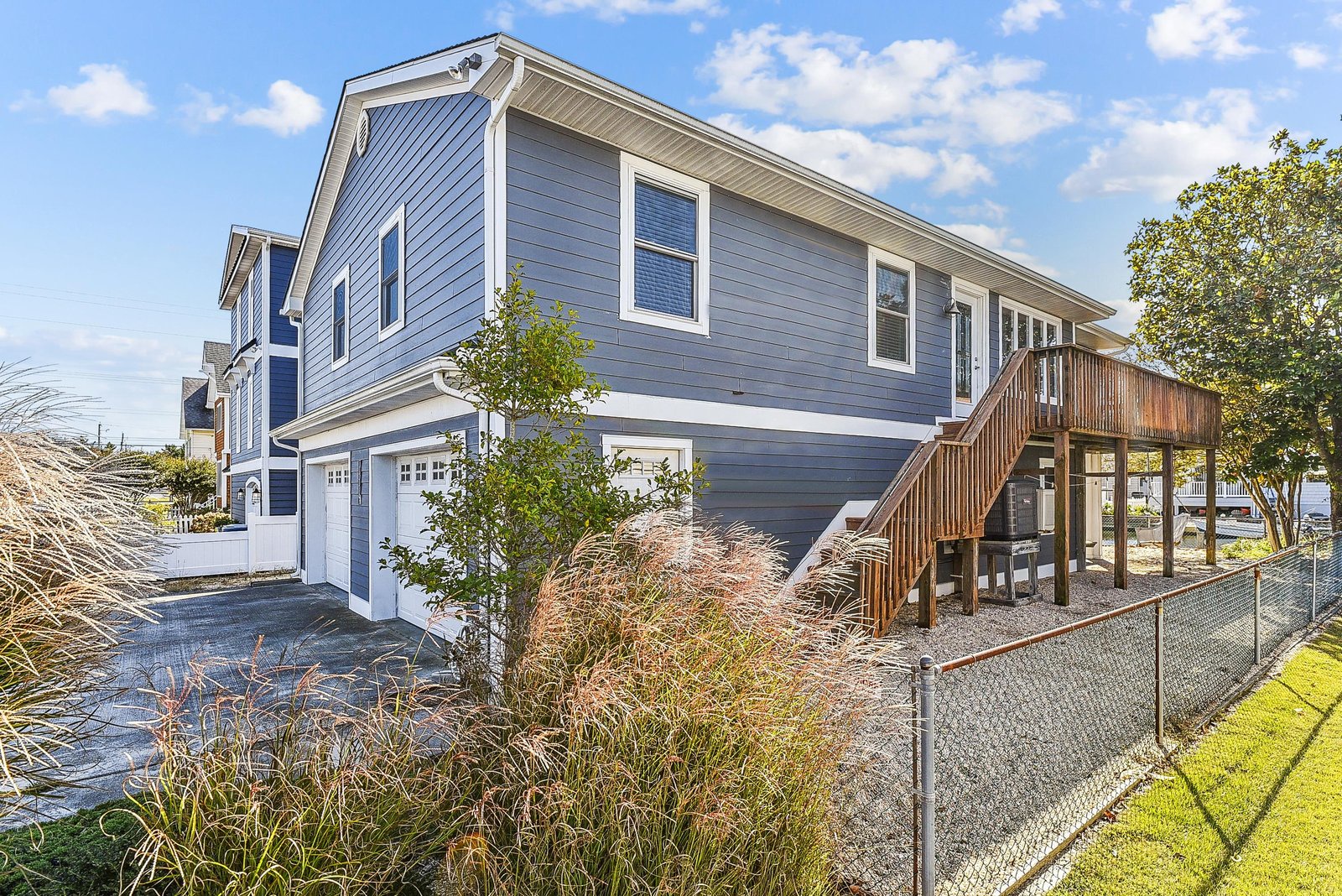A coastal home featuring a two-car garage, elevated deck, and fenced yard, nestled in a quiet neighborhood with easy access to the water.