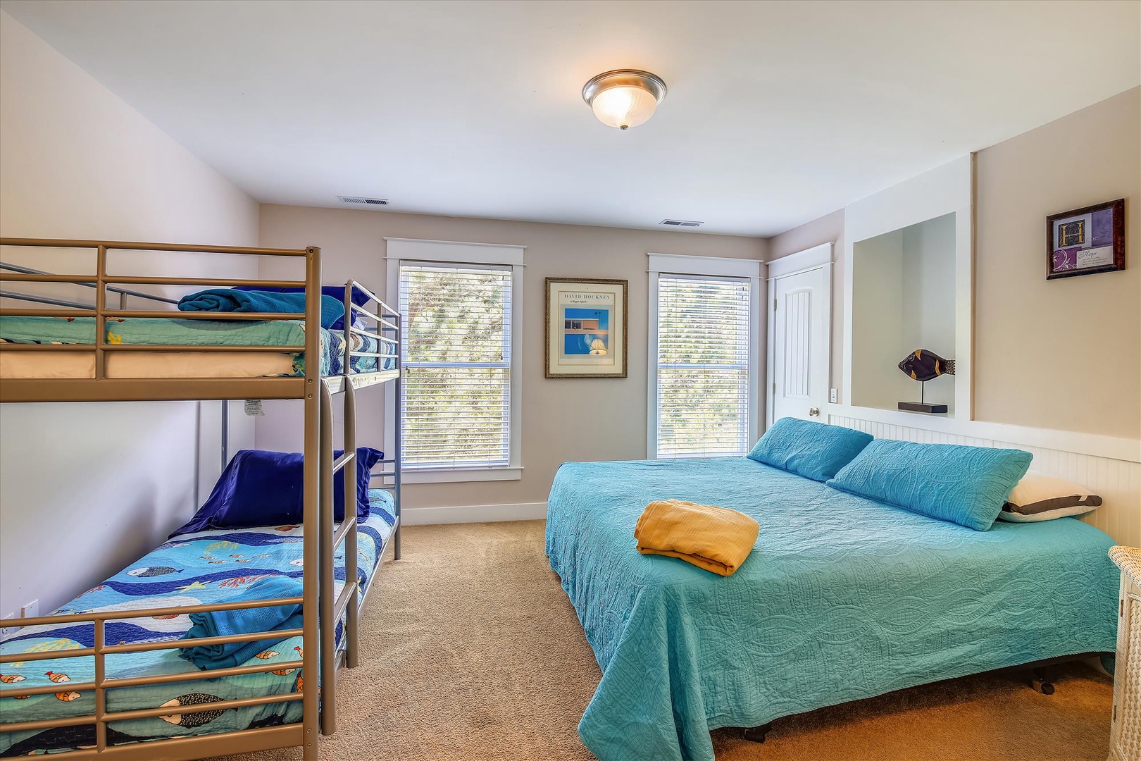 Your bright, spacious bedroom features a comfortable queen bed and a fun bunk bed, perfect for families. Natural light fills the room through two large windows, while coastal blue linens add a relaxing touch.