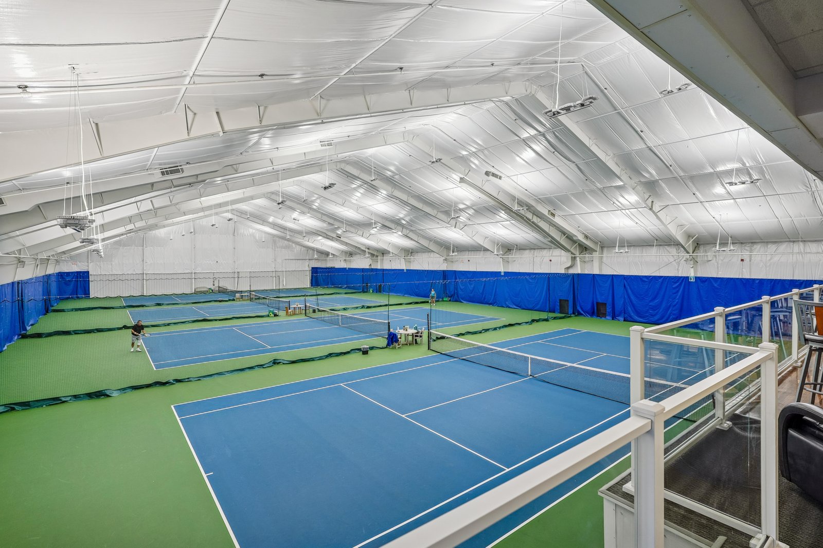 The indoor tennis facility features multiple pristine courts with professional-grade surfaces, perfect for all-season play regardless of weather.