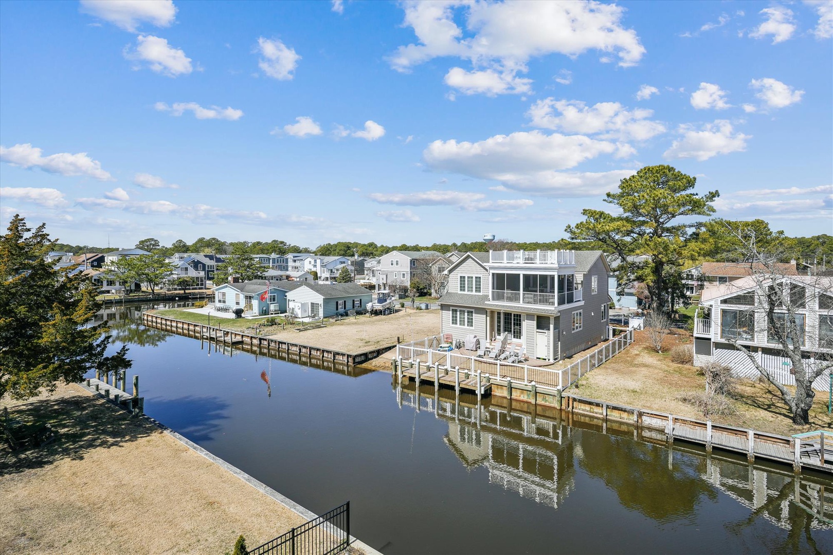 Waterfront community with private docks, peaceful canal views, and coastal homes nestled among mature trees under a bright blue sky.