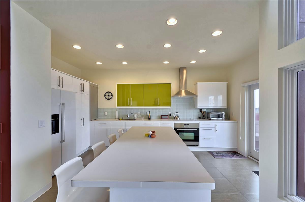 Step into your own sunlit kitchen, where crisp white surfaces meet cheerful yellow cabinetry. Gather around the spacious island for morning coffee or meal prep under soft recessed lighting.