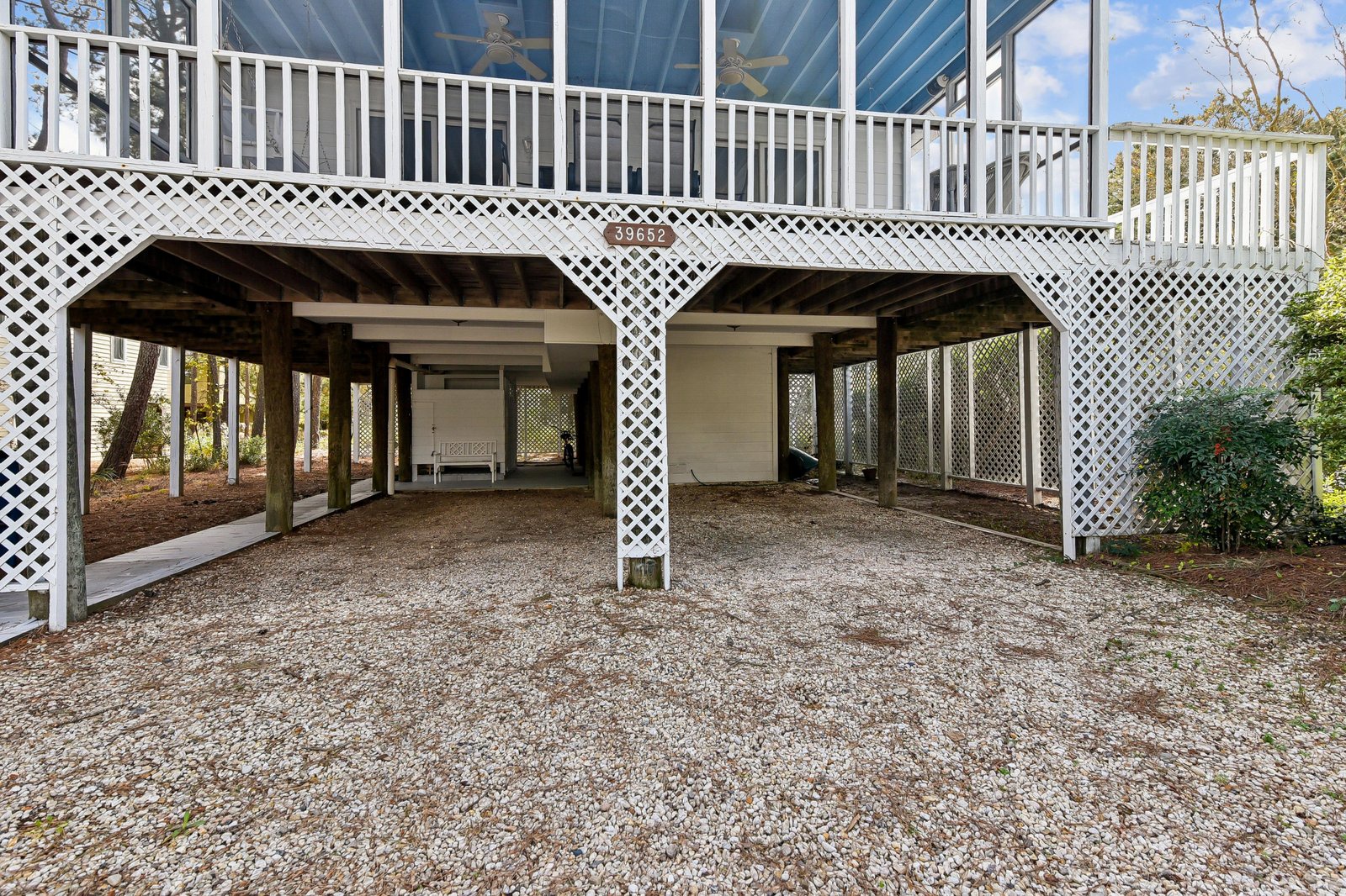 Covered parking area with gravel driveway located beneath the elevated property structure at 39652.