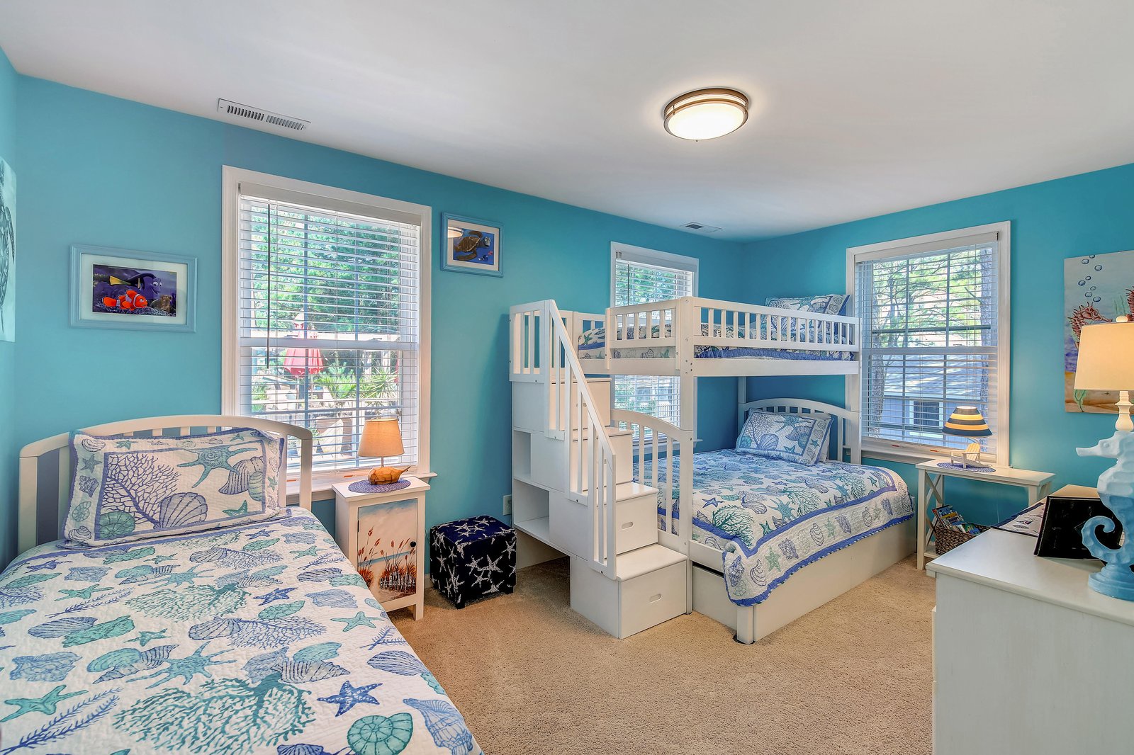 Your kids will love this ocean-themed bedroom with its bunk bed and cozy twin bed, all bathed in cheerful turquoise. Bright windows fill the room with natural light, making it a fun and inviting space.
