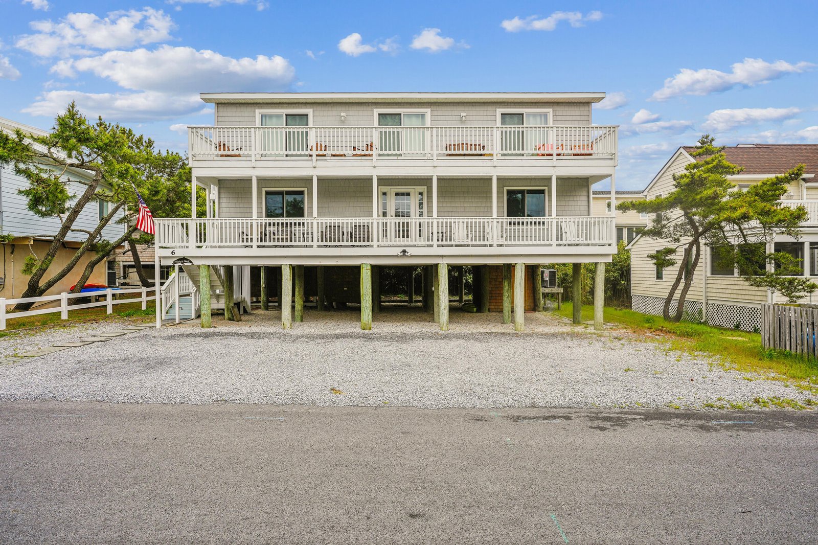 Three-story beachside property with spacious wraparound balconies, elevated construction for coastal protection, and ample parking beneath the home, located just steps from the shore.