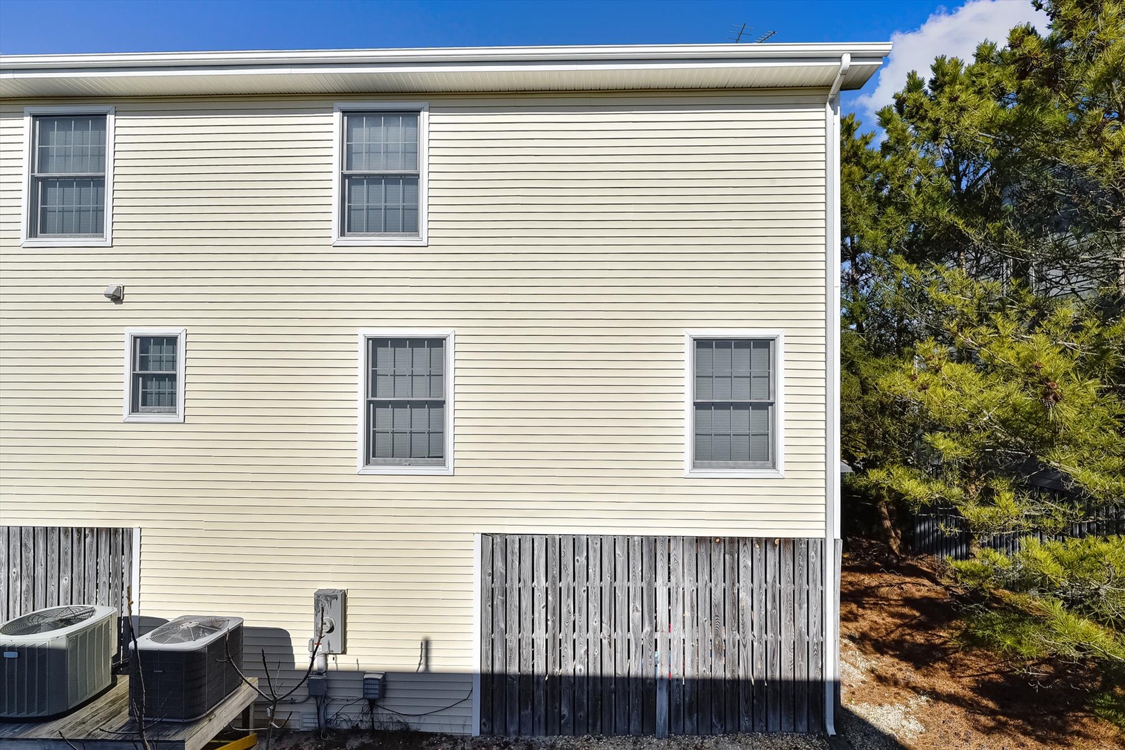 The property's exterior features classic siding and multiple windows, set against a backdrop of tall trees that provide natural privacy and shade.