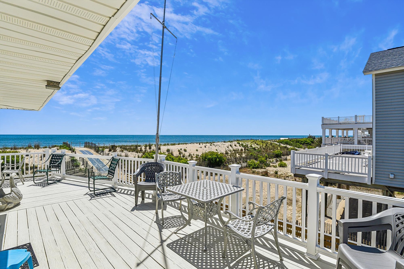 Beachfront property with deck access, ocean views, and natural dune landscape between the home and waterfront.