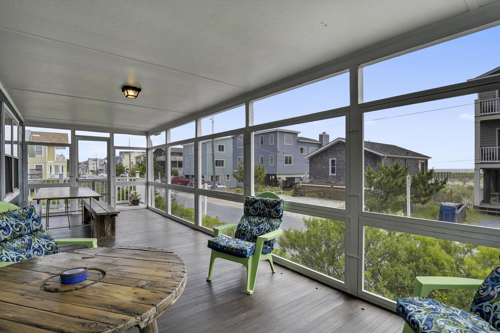 Screened porch with comfortable seating where you can unwind and watch the coastal neighborhood come to life around you.
