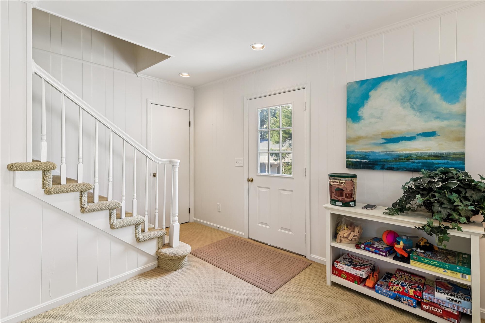 Your coastal-themed entryway welcomes you with nautical artwork, organized game storage, and charming woven stair runners.