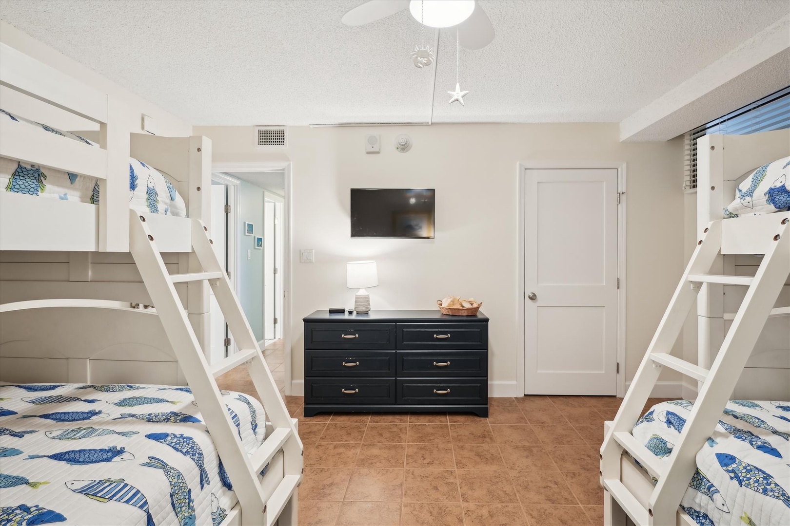 Your beachside bunk room with nautical bedding, entertainment center, and cozy lighting creates the perfect family retreat.