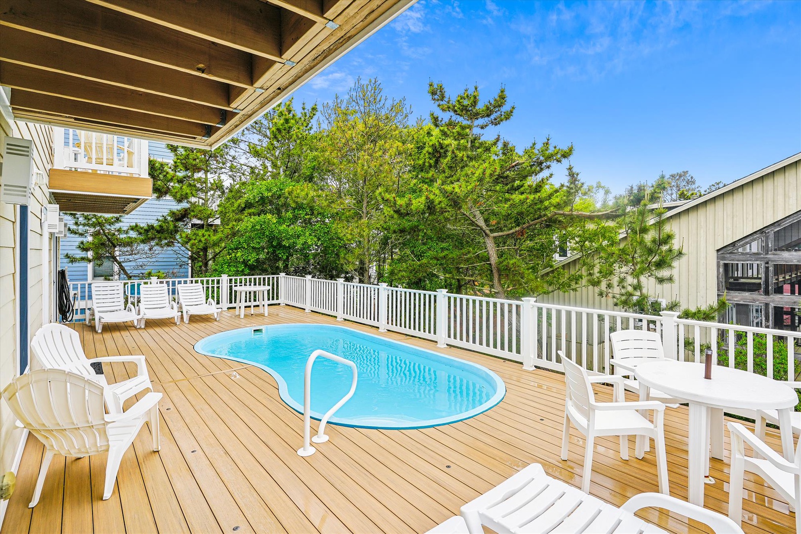 Step onto your private deck where a sparkling pool awaits, surrounded by lounge chairs perfect for sunbathing. Lush green trees provide a peaceful backdrop for your getaway.