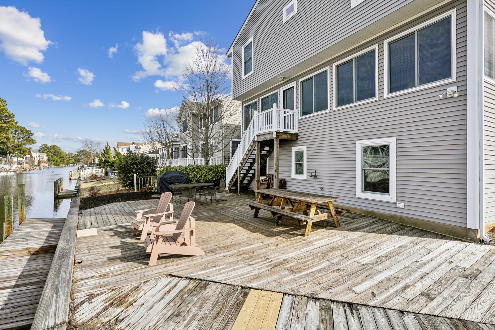Waterfront property featuring spacious deck with outdoor seating, BBQ facilities, and direct water access.