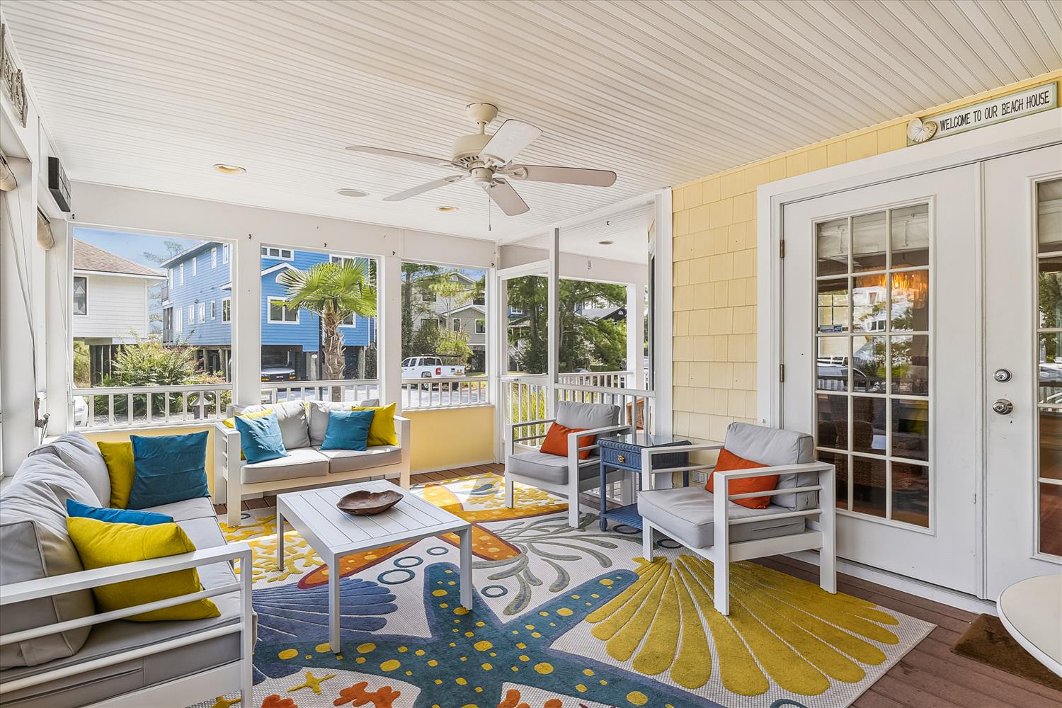 Relax on your private screened porch with ceiling fan and vibrant coastal décor. Large windows frame the neighborhood views while you unwind in comfort.
