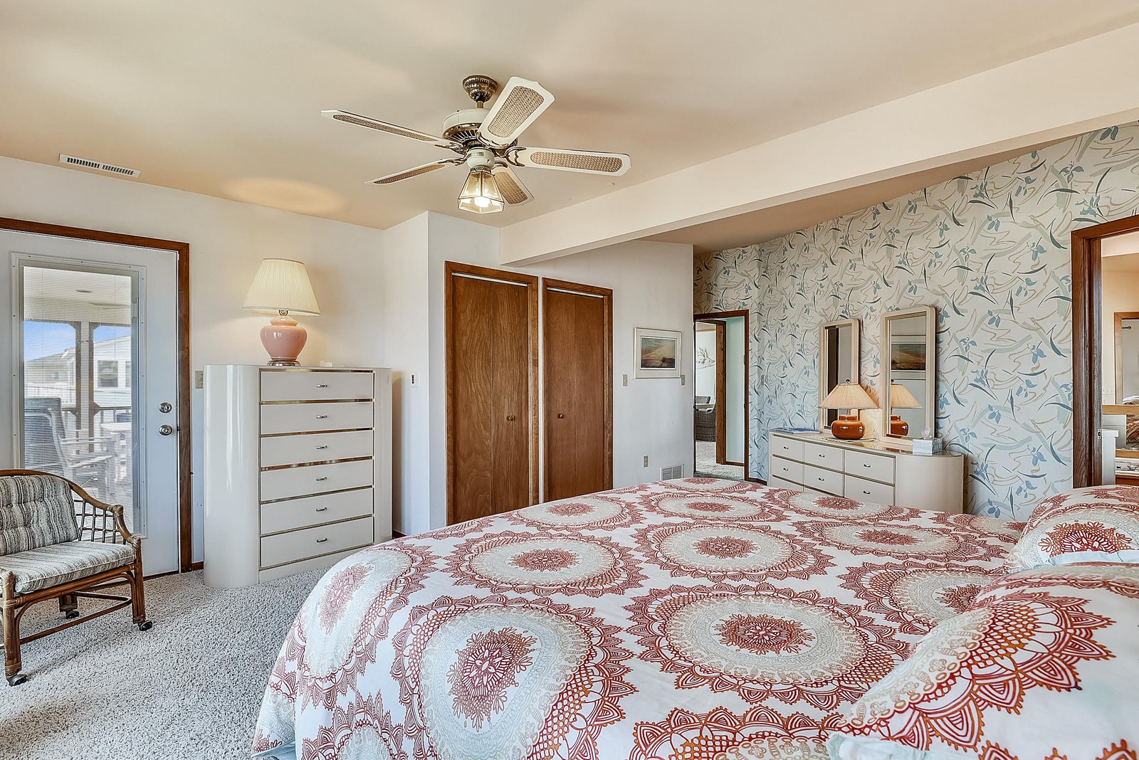 Inviting bedroom with plush king bed, ceiling fan, and ample storage. Charming accent wall and natural light create a peaceful retreat for restful nights.