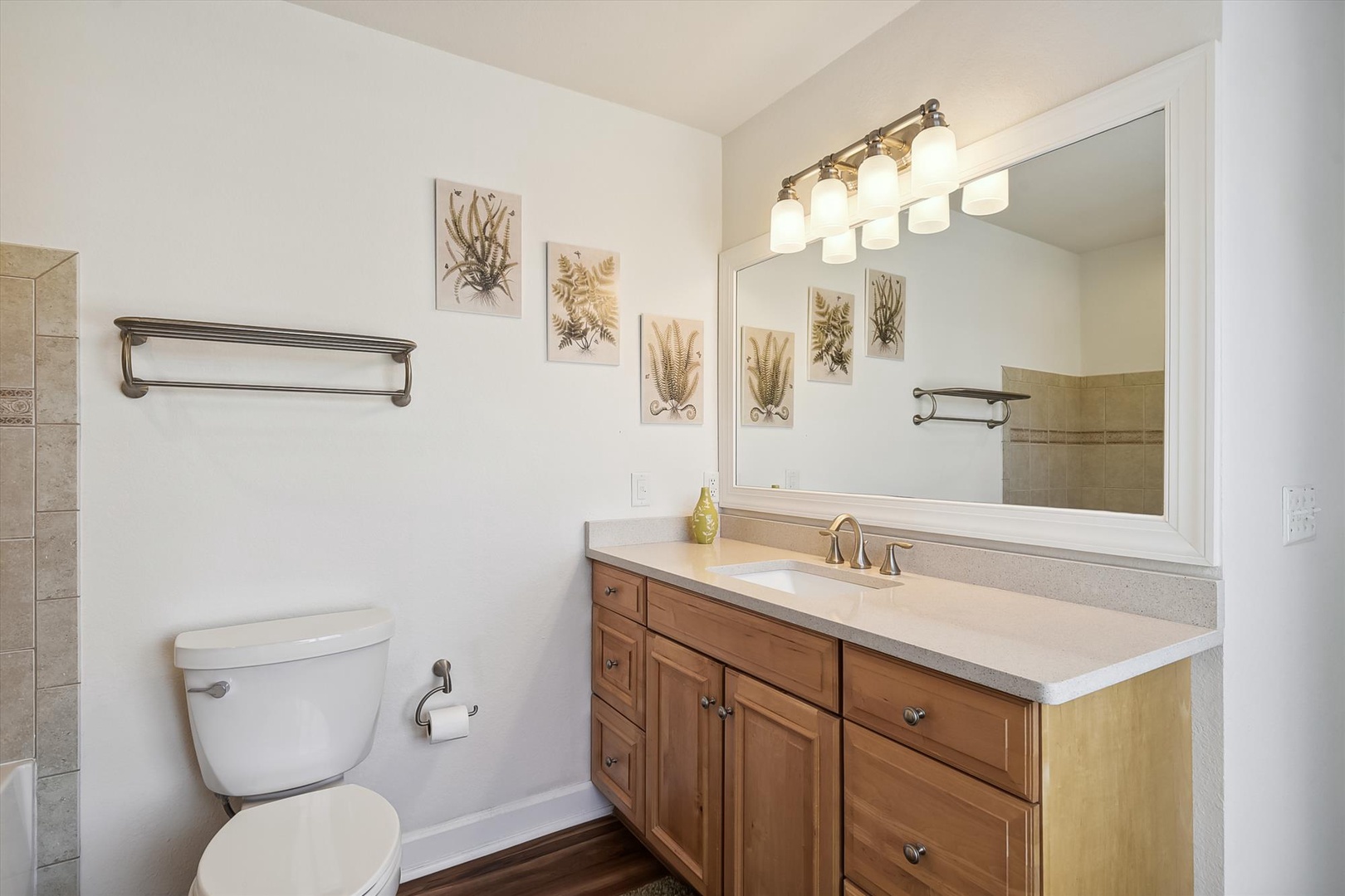 Step into your private bathroom, where botanical art and warm wood tones create a soothing retreat. The spacious vanity and bright lighting make every morning feel refreshing.