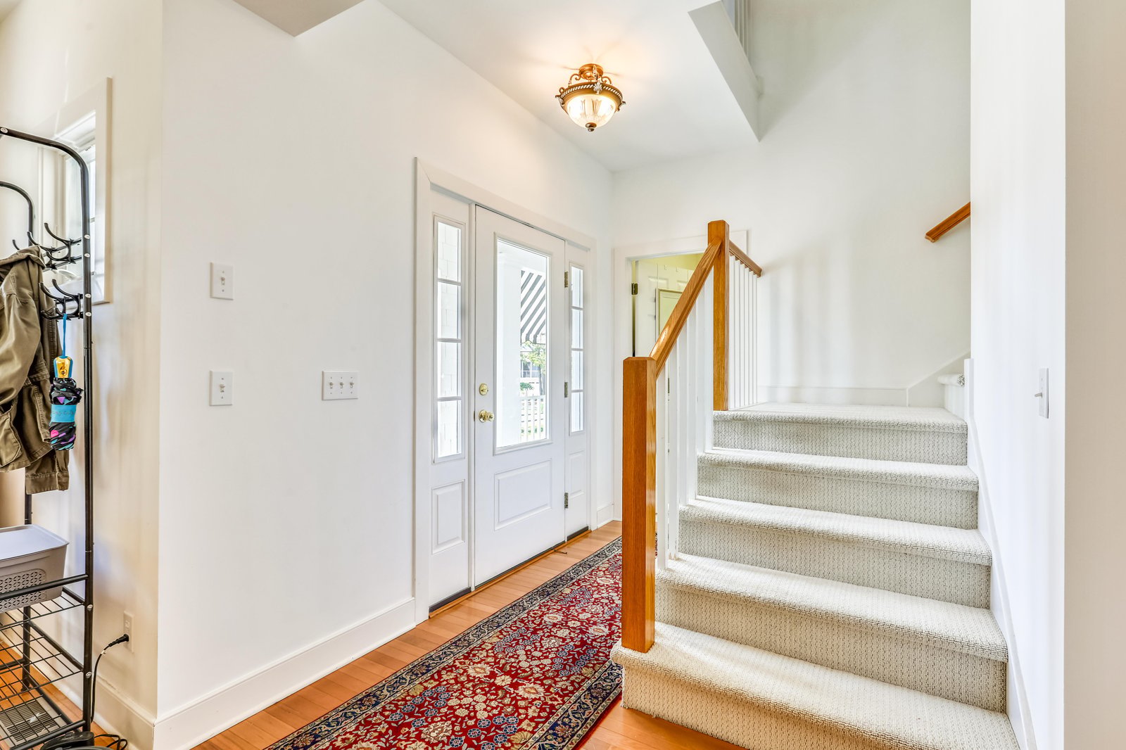 Step through the elegant glass-paneled front door into your bright, welcoming entryway with warm hardwood floors and cathedral ceilings that create an airy, inviting first impression.