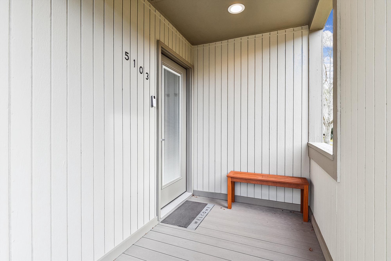 The entrance to unit 5103 features a covered porch area with a simple wooden bench, welcoming visitors to the property.