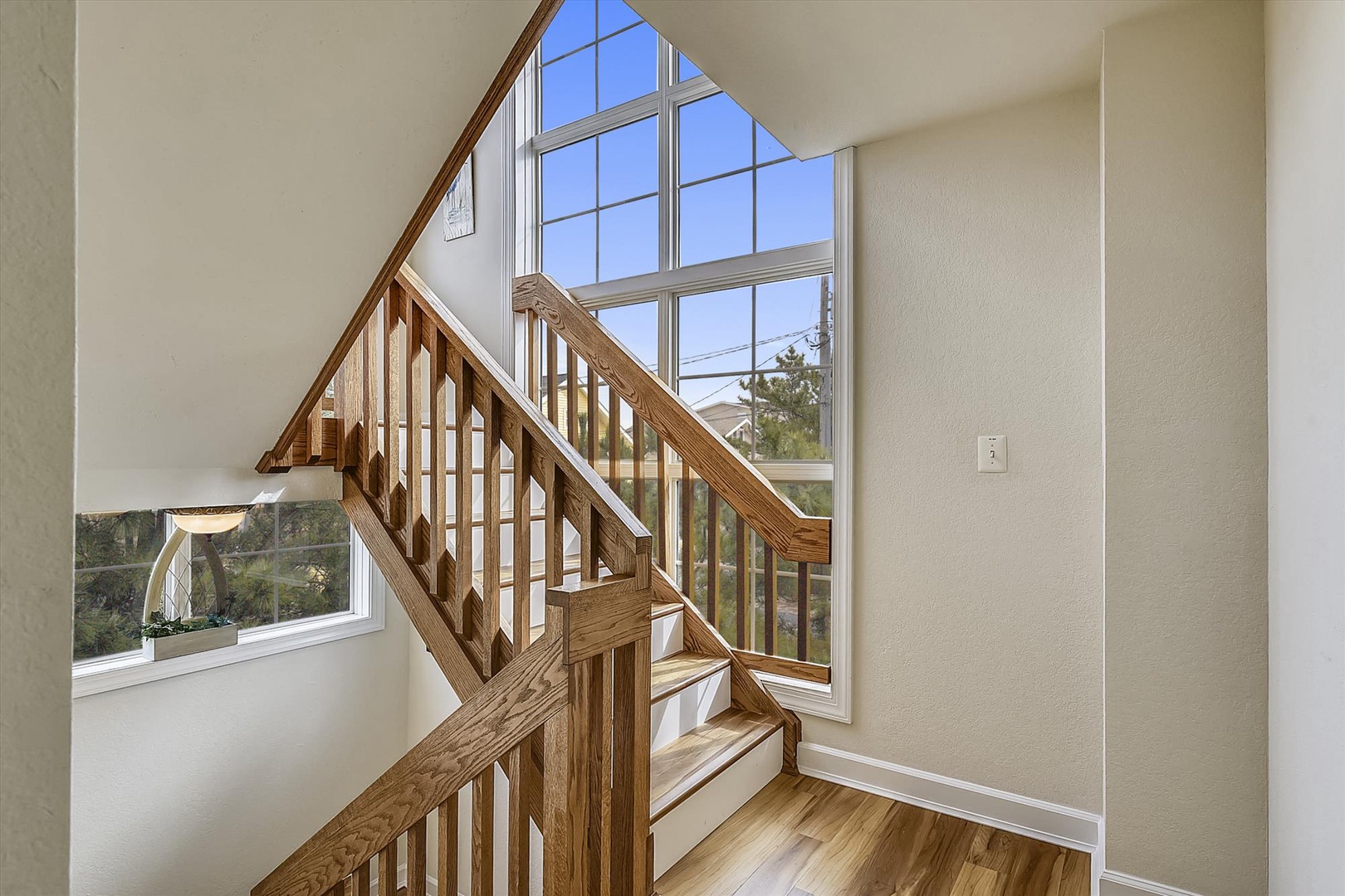 Sunlight streams through soaring windows as you climb the elegant wooden staircase, creating a bright, welcoming entrance to your retreat.