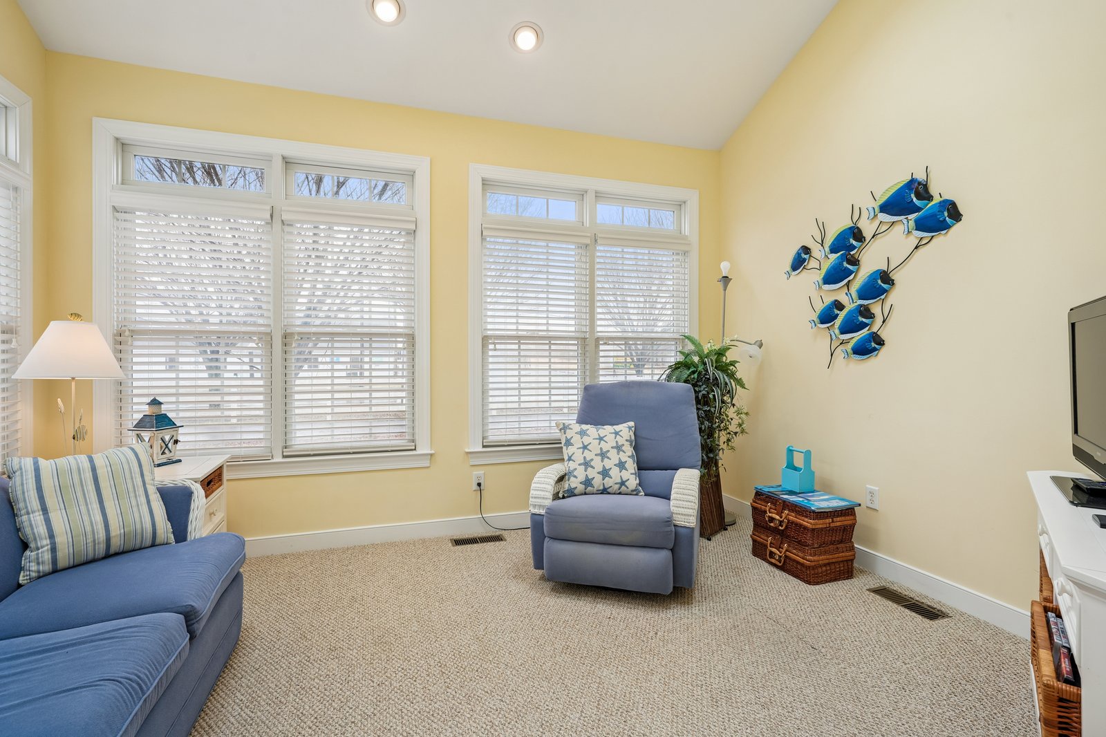 Unwind in your cheerful living space with comfortable blue seating, warm natural light, and coastal touches that create the perfect retreat.