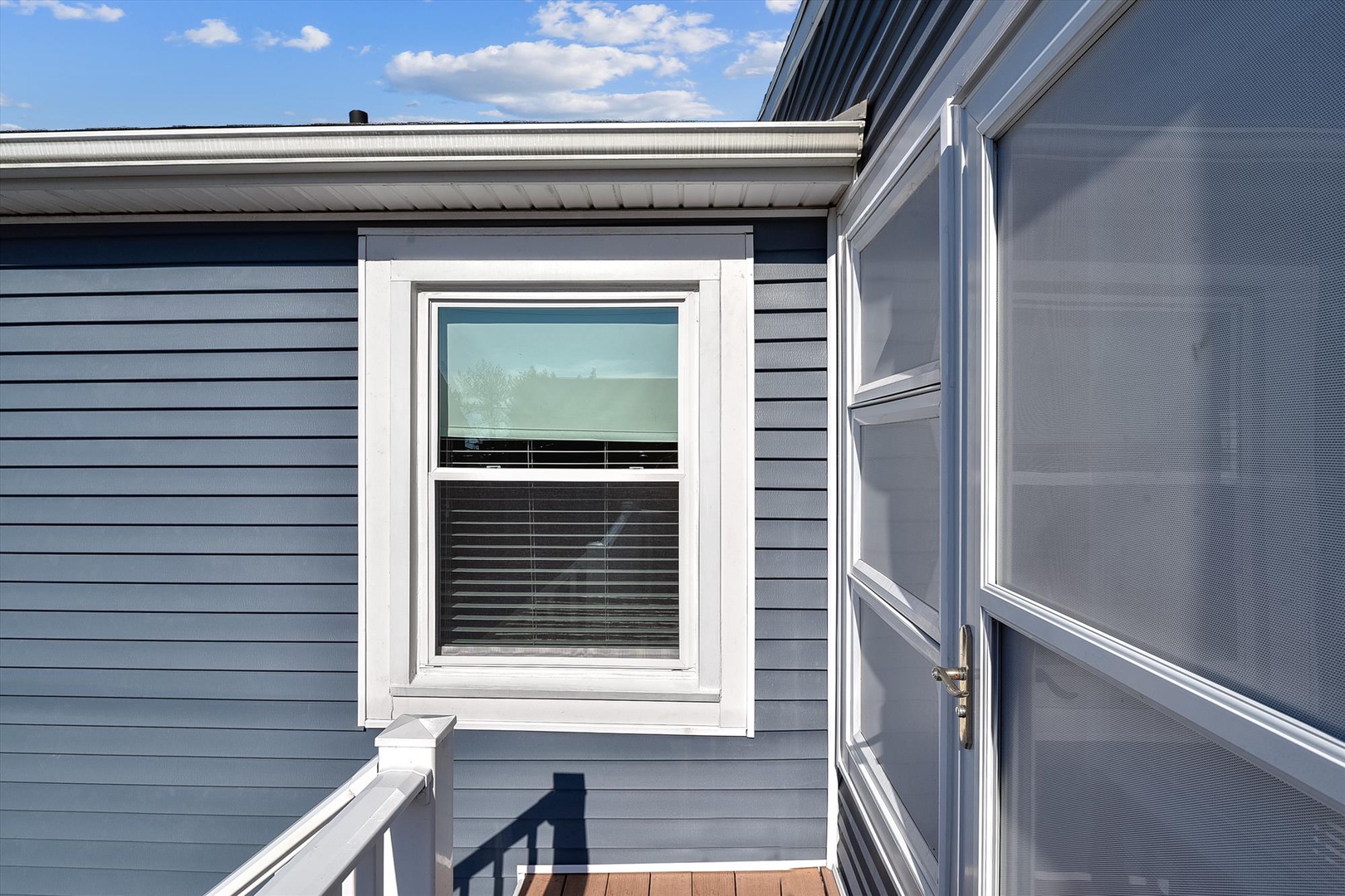 Modern blue-gray siding defines this property's clean exterior lines, complemented by crisp white trim and bright blue skies overhead, creating a fresh coastal-inspired aesthetic.