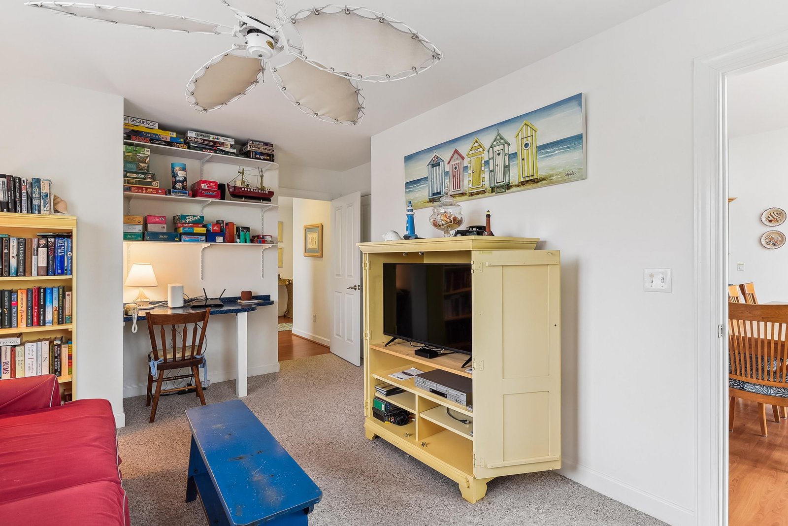 Curl up with a favorite book in this cozy, light-filled space, where a cheerful ceiling fan, plentiful shelving, and beach-themed touches invite your downtime and quiet reflection.