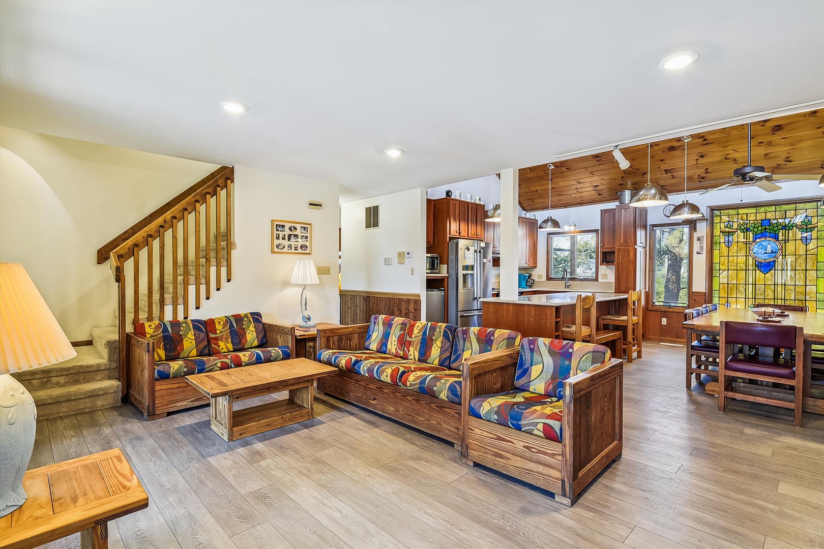 Step into your inviting open-concept living space where warm wood furnishings and vibrant upholstery create a welcoming retreat. Relax on the colorful sofas, gather around the dining table, and enjoy the seamless flow to your fully-equipped kitchen.