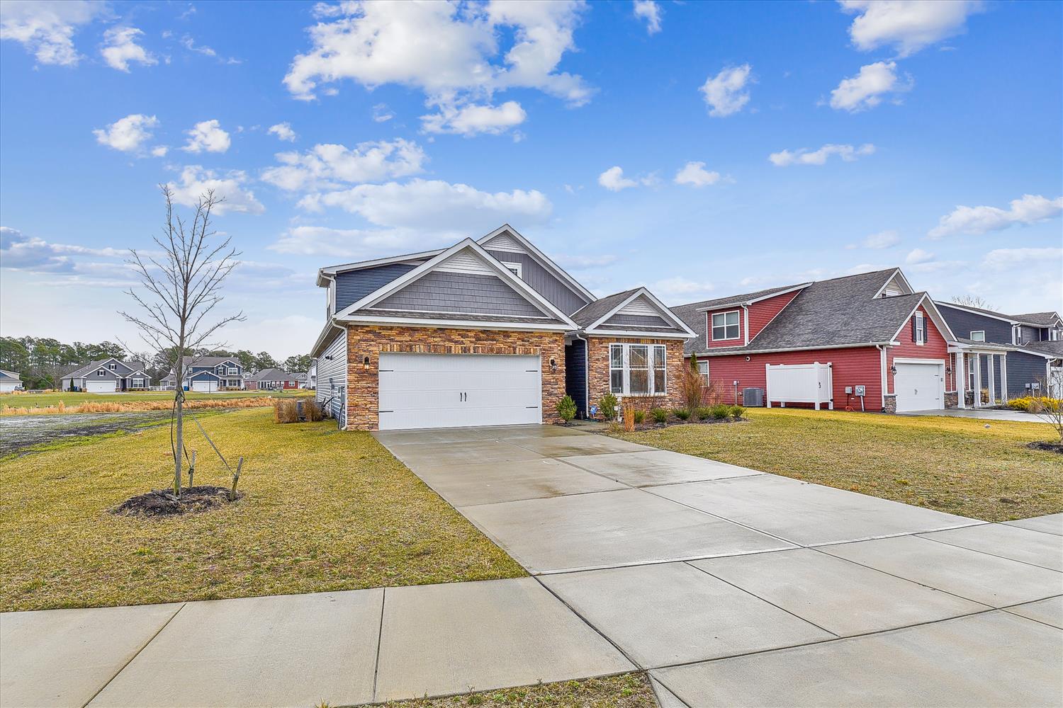 The property is located in a quiet residential neighborhood with well-maintained homes and open green lawns under expansive blue skies.