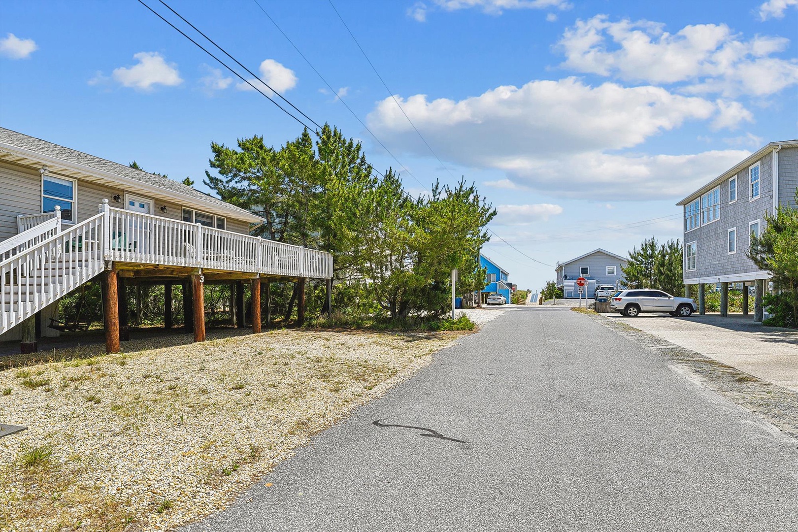 Quiet coastal neighborhood with beach homes on stilts, mature trees, and easy access to sandy shores and island living.