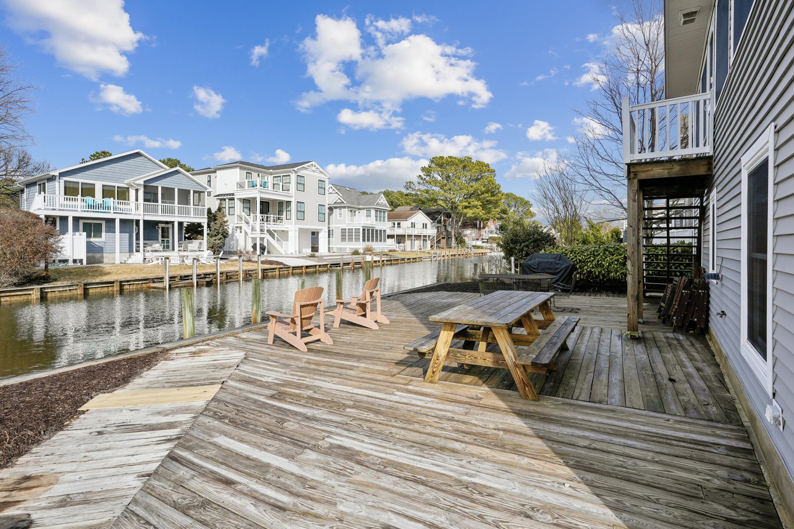 Private waterfront deck overlooks a peaceful canal with charming homes across the water. Relax in the rocking chairs or gather around the picnic table for meals with a view.