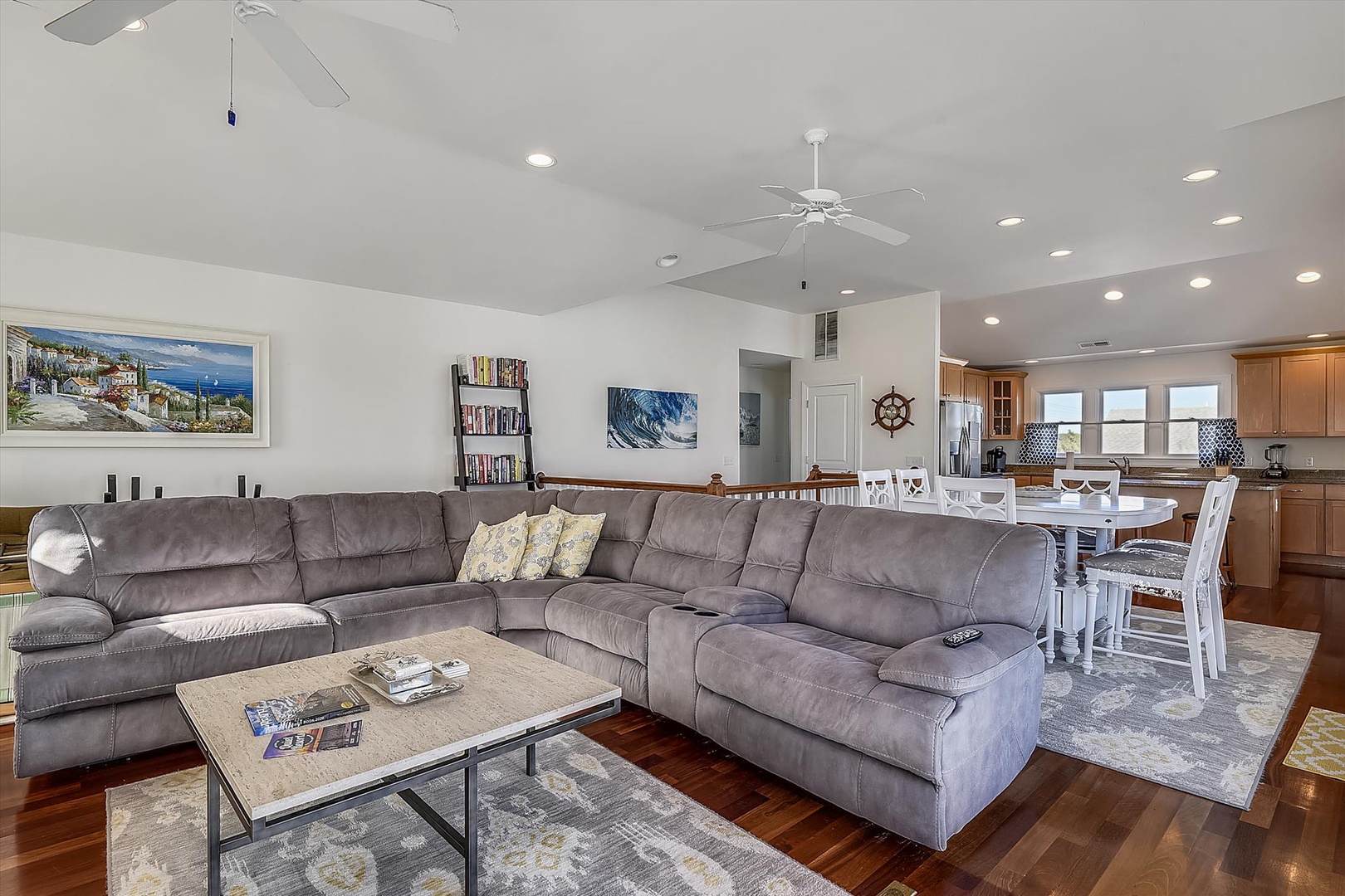 Settle into your spacious living area, where a plush sectional invites you to unwind. Bright coastal artwork and open-plan layout create an airy, welcoming atmosphere perfect for gathering.