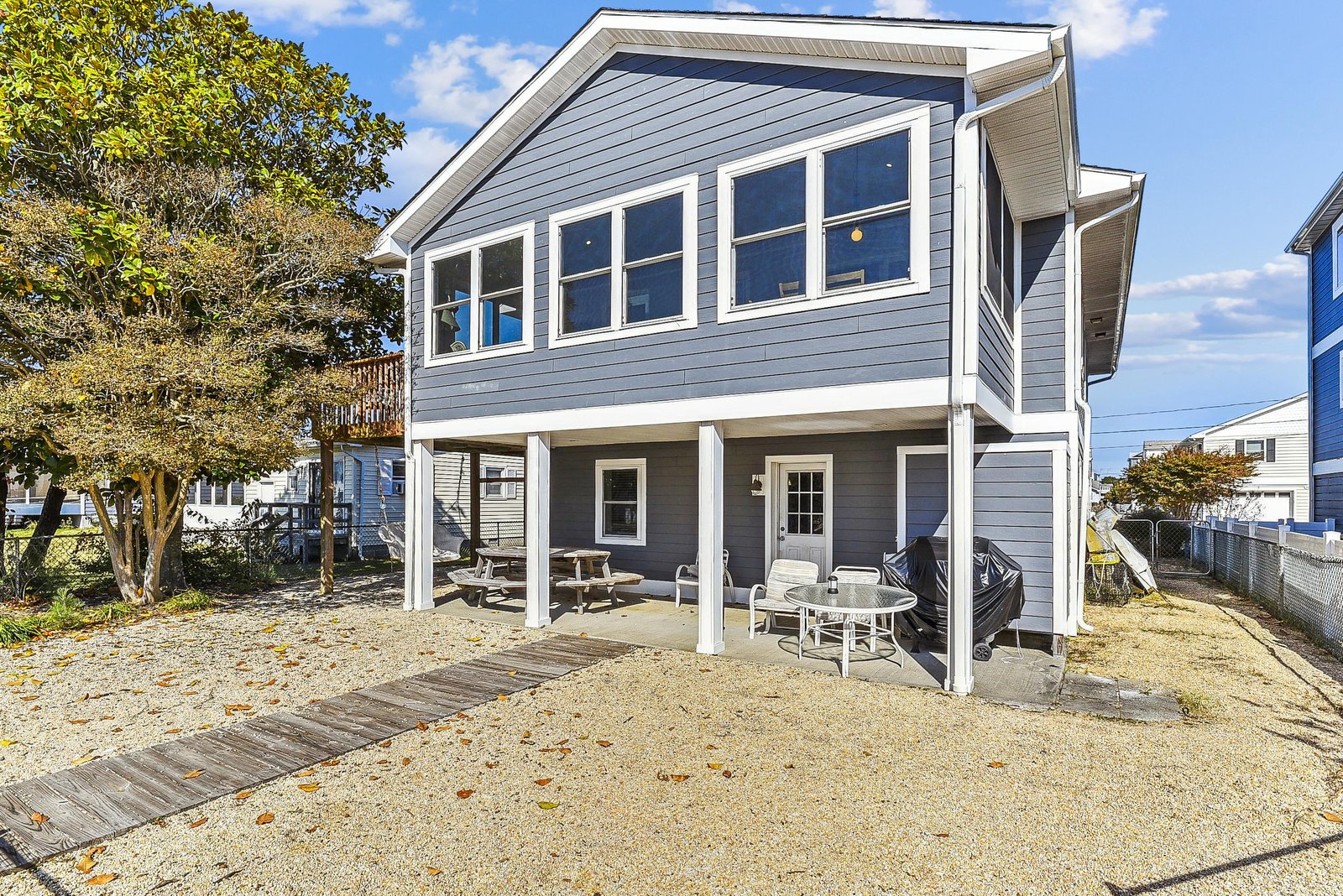 A welcoming beach retreat with elevated living, featuring a covered ground-level patio with dining and relaxation areas ready for your coastal getaway.