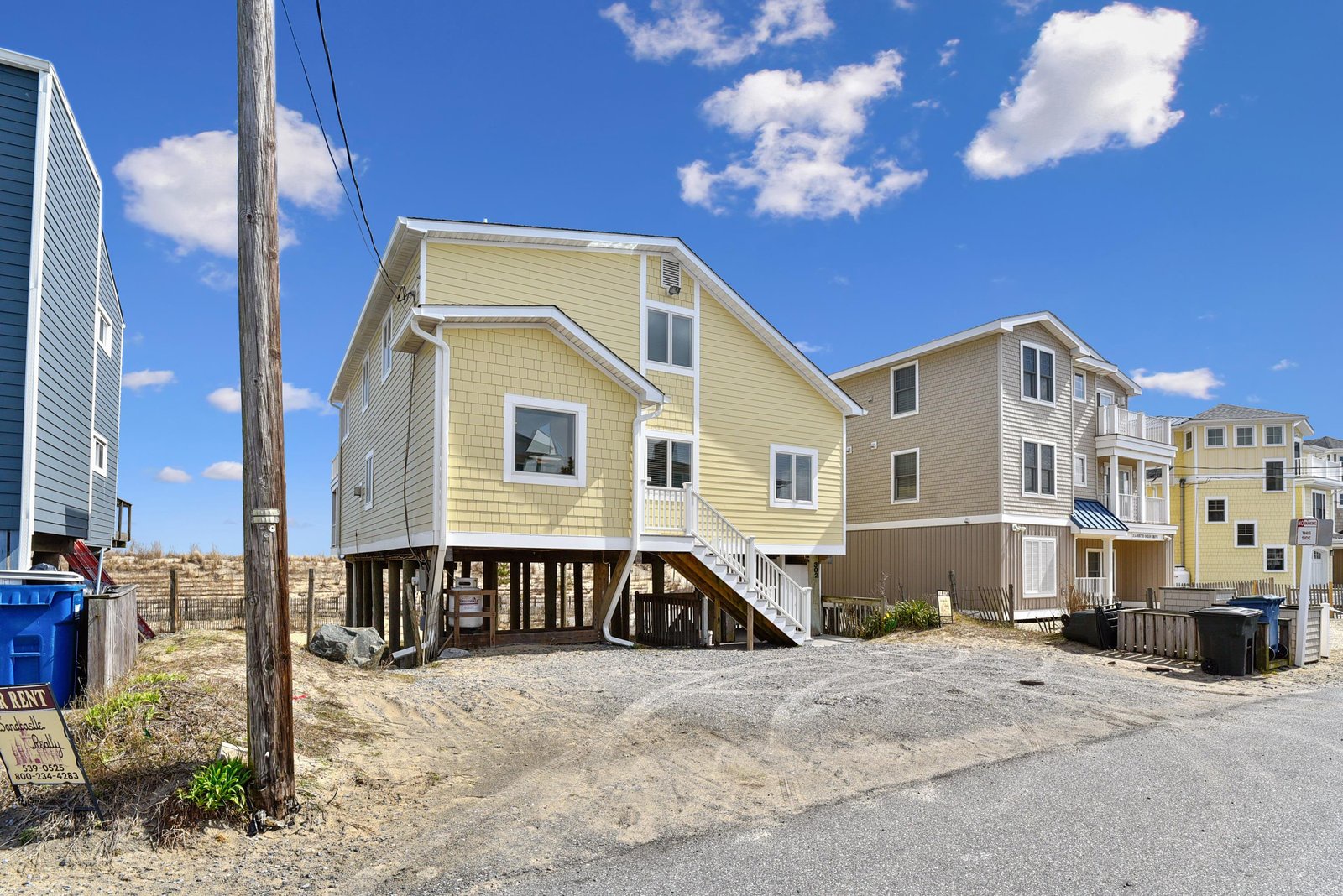 Cheerful yellow beach house elevated on sturdy pilings, perfectly positioned near the shore. Ample parking makes arrival easy as you settle into your coastal escape.