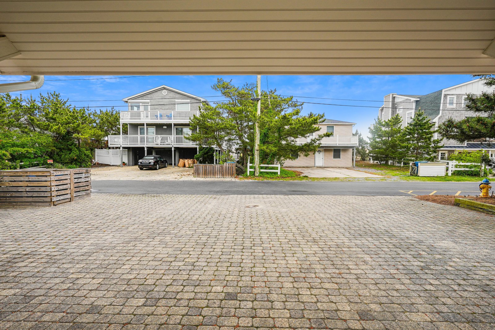 Your vacation home rests in a peaceful residential neighborhood, surrounded by mature trees and coastal charm. This spacious brick-paved driveway and covered parking area offer convenience and ease upon arrival.