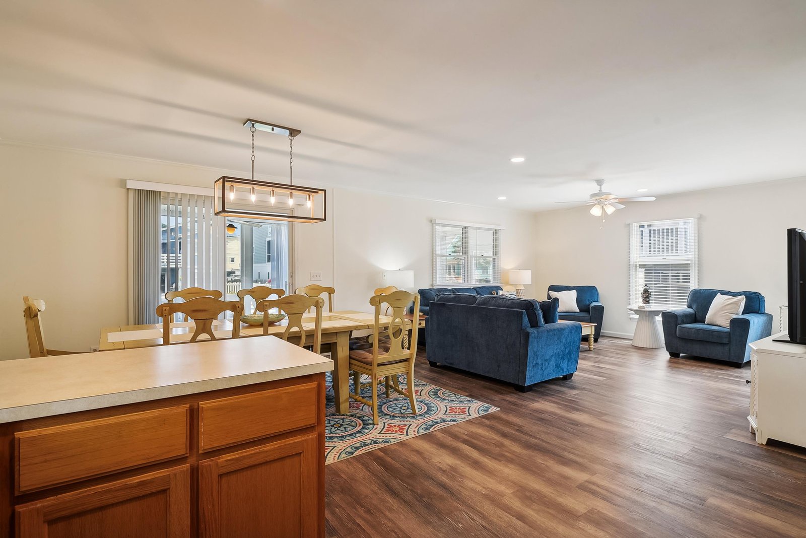 Sink into plush blue armchairs or gather around the spacious dining table—your bright, open-plan retreat invites easy togetherness with warmth underfoot and sunlight pouring through every window.