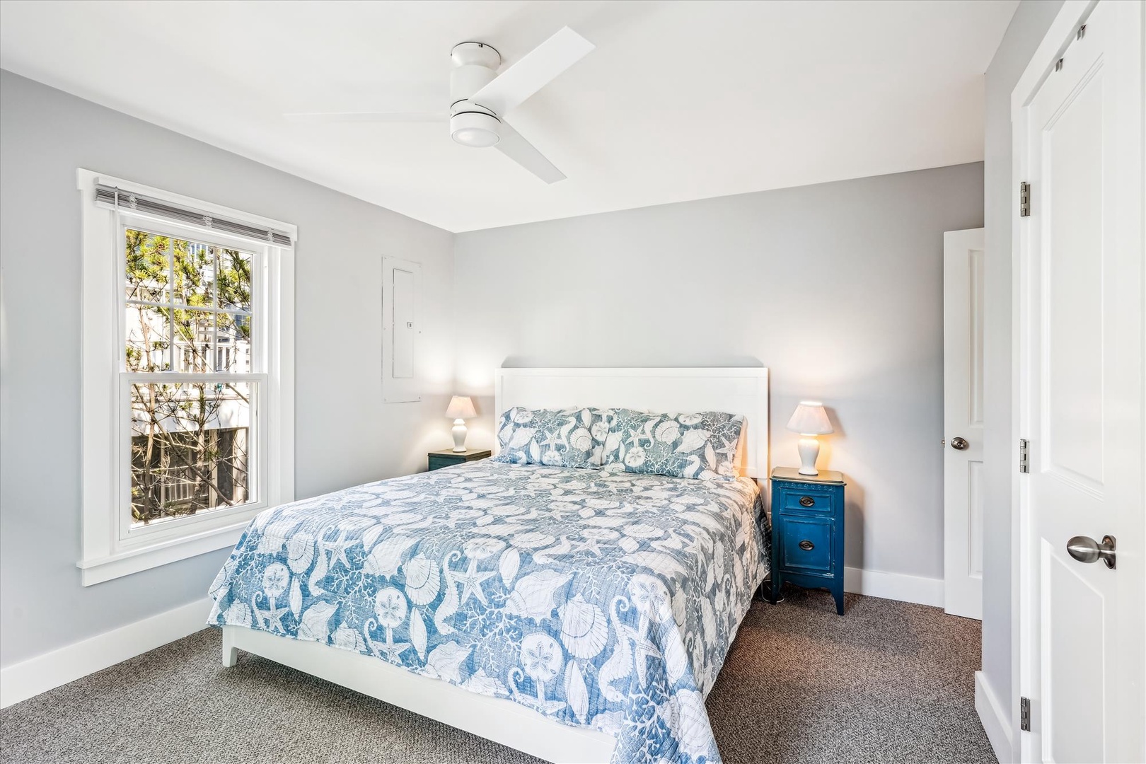 Drift off in your serene bedroom featuring soft blue elephant-print bedding, warm lighting, and a peaceful street view.