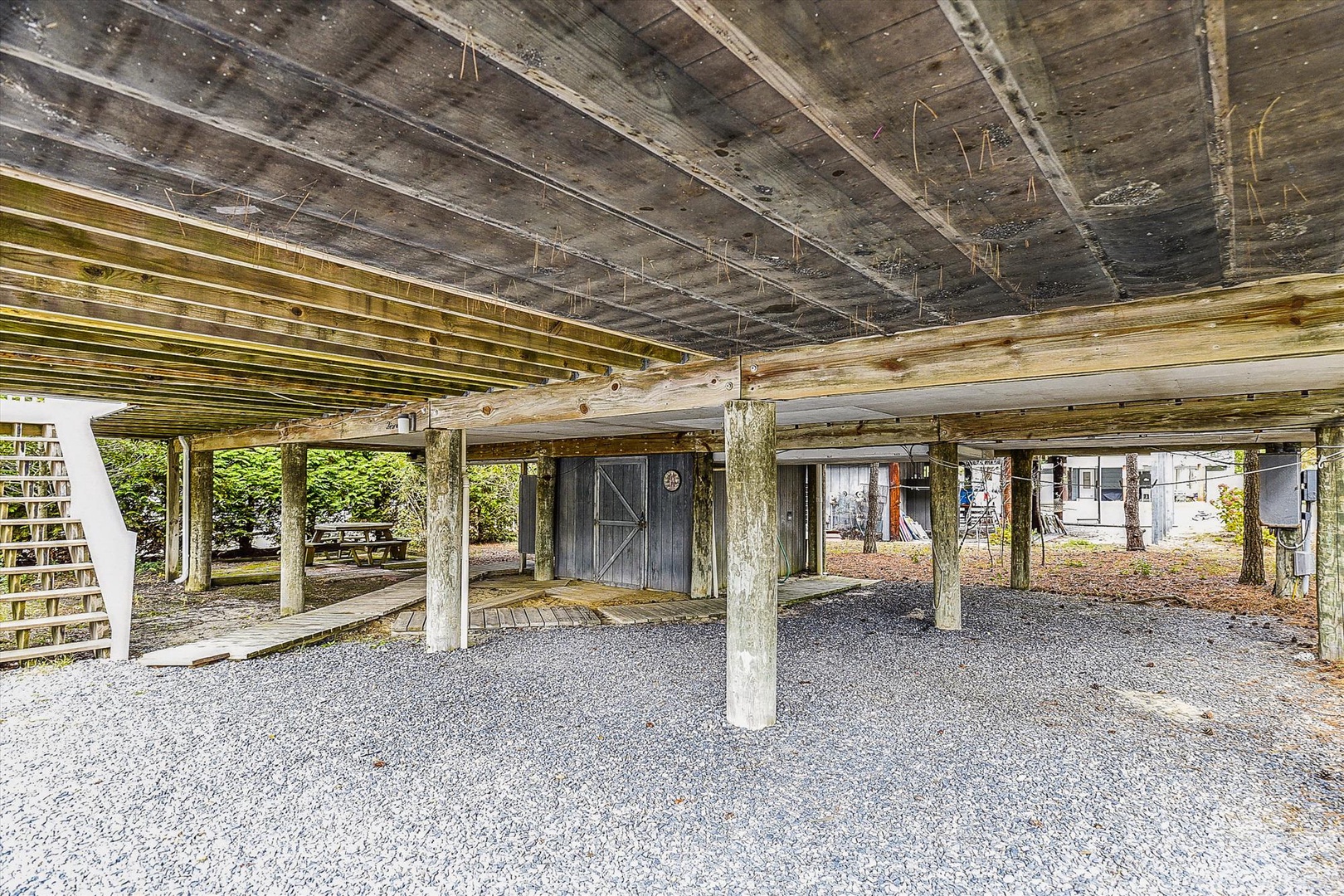 Covered parking beneath the property provides sheltered vehicle storage with rustic wooden post-and-beam construction and convenient ground-level access.