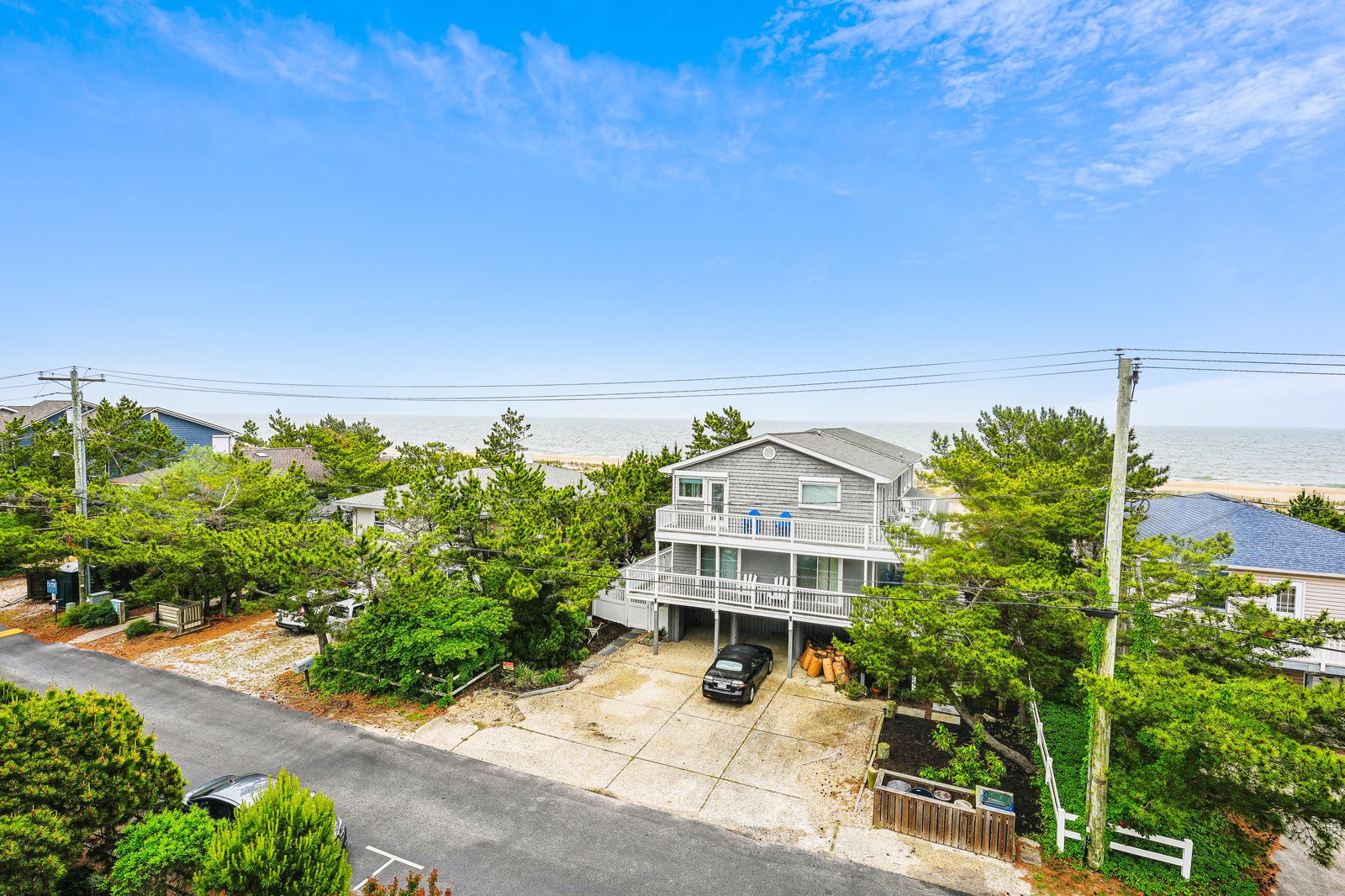 This coastal property sits just steps from the beach, nestled in a quiet residential area with lush trees and ocean breezes all around.