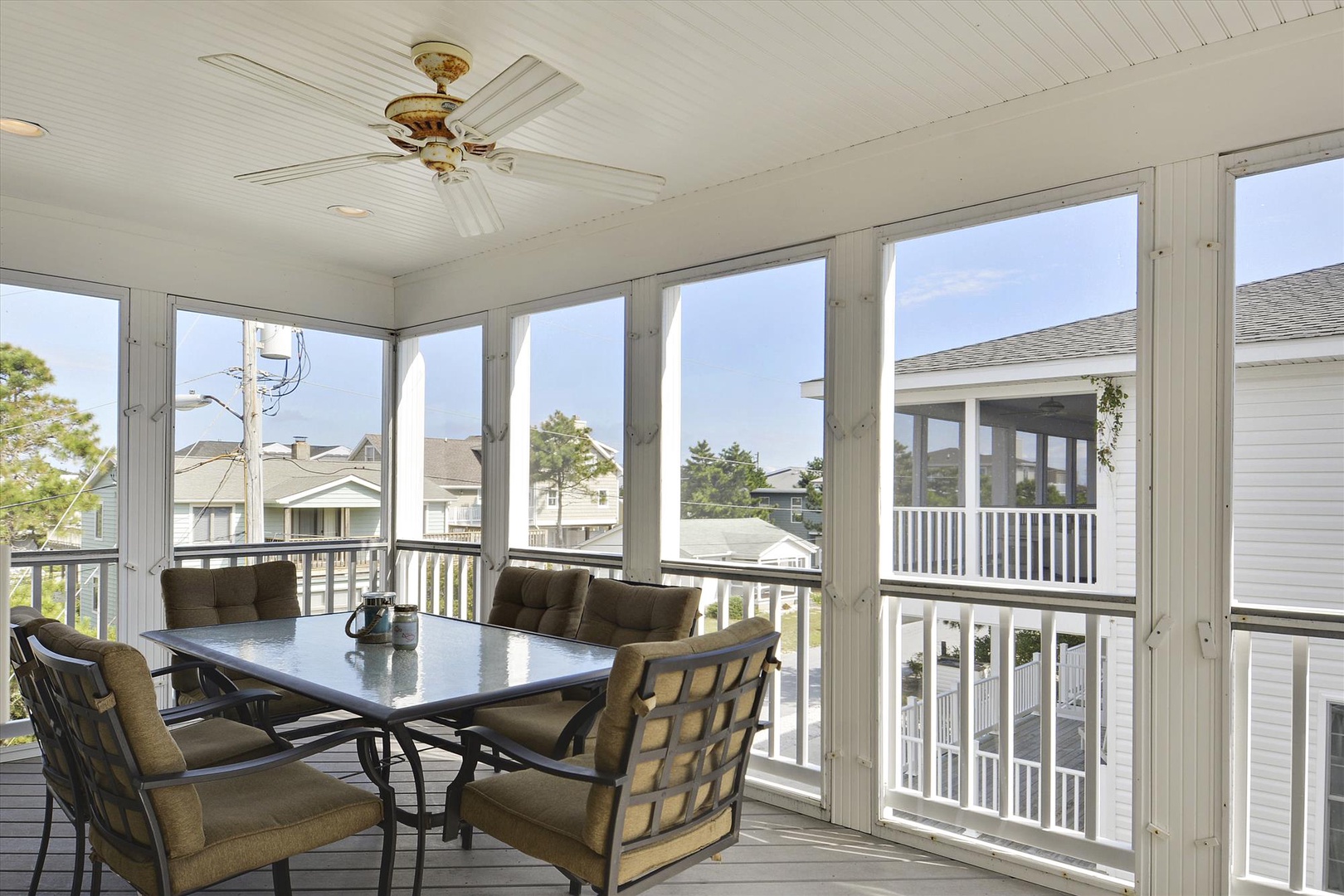 Enjoy your morning coffee or evening meals in this enclosed sunroom, where panoramic windows frame views of the peaceful neighborhood and comfortable seating invites you to relax year-round.