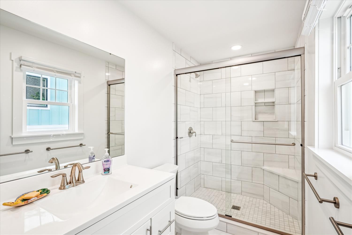 Your pristine white bathroom features elegant subway tile, a glass-enclosed shower, and sparkling countertops that create a spa-like retreat.