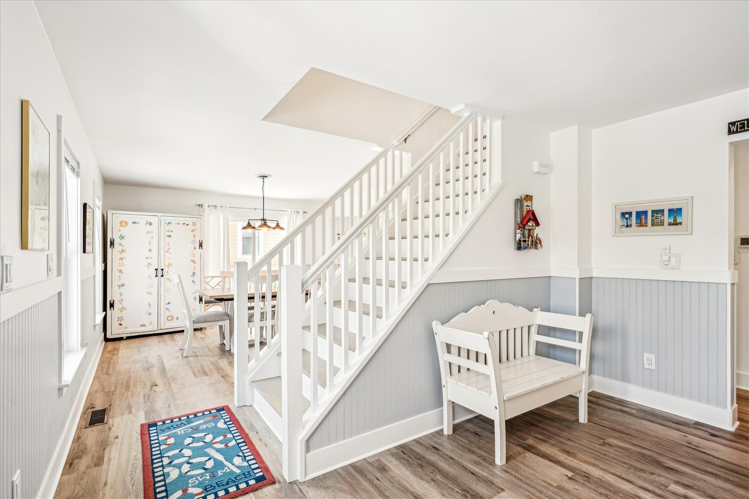 Step into your welcoming entryway with charming coastal touches, featuring a cozy reading nook beneath elegant white stairs.
